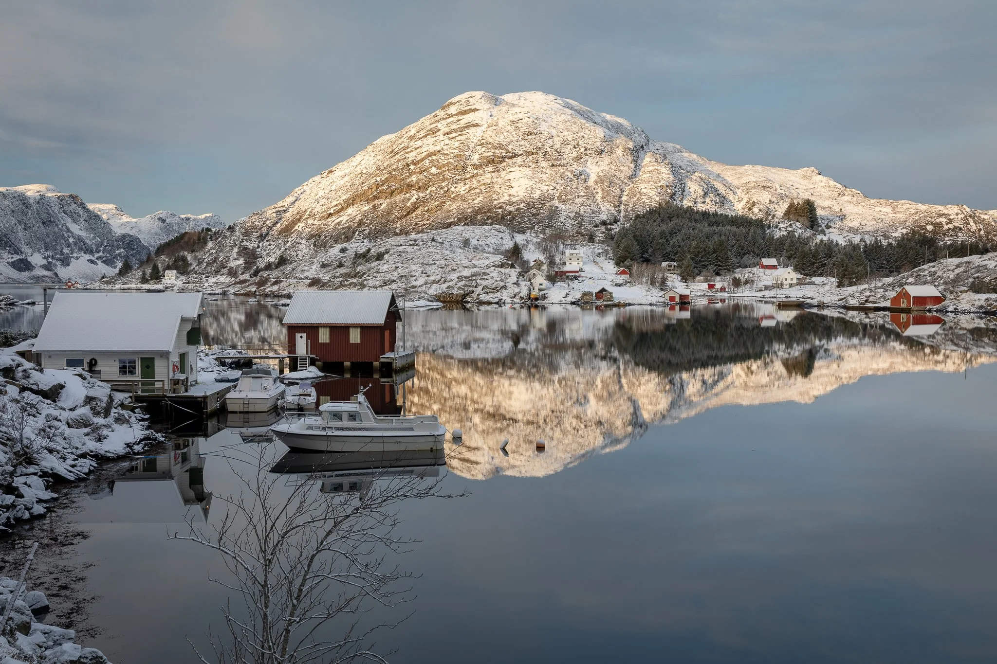 Tytingevågen ved Krabbestig – kystlandskap med snødekte lier, små naust og blankt vann innerst på Husevågøy.