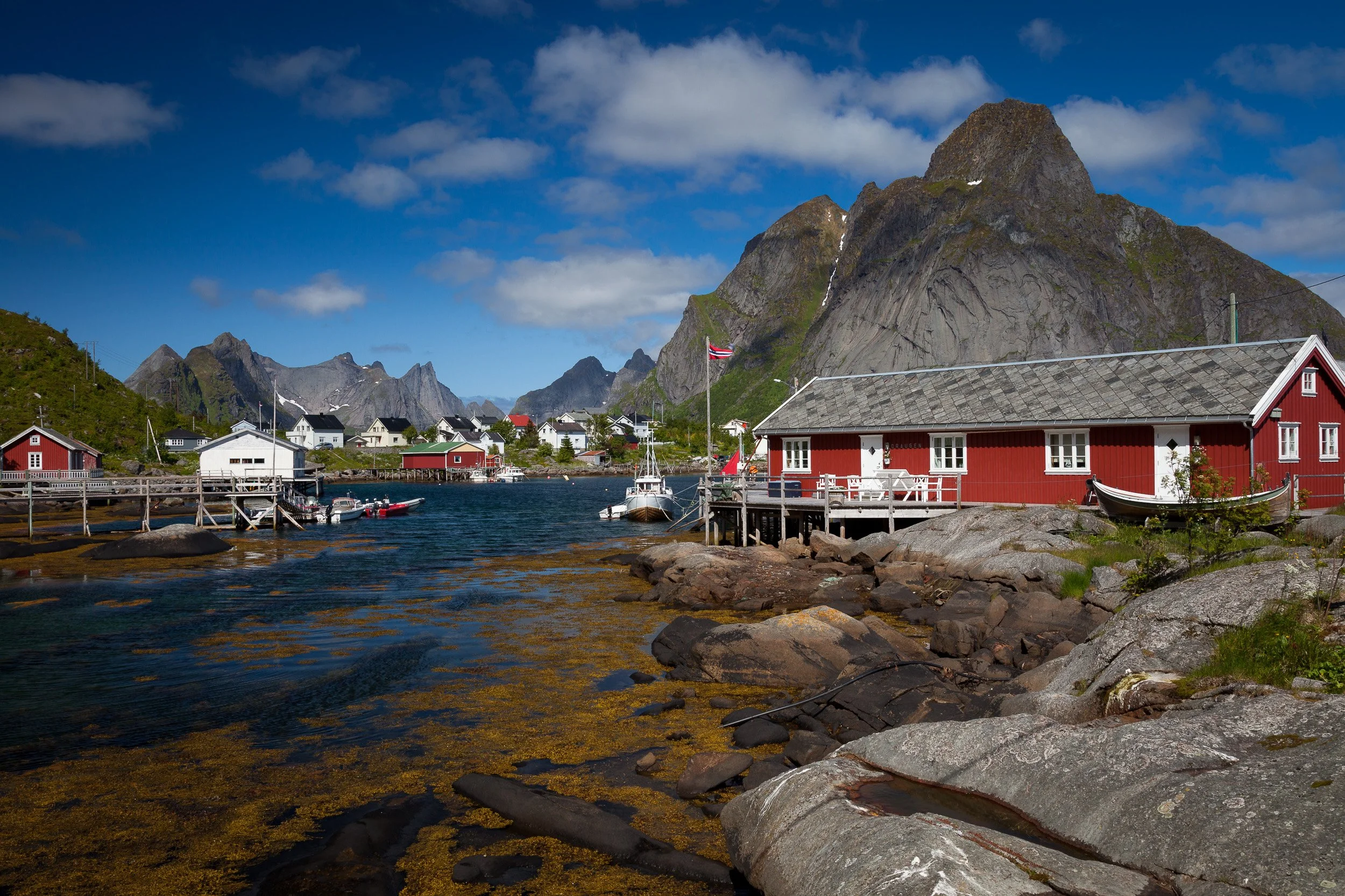 Fisherman’s cabins in Reine, Lofoten Islands, Norway – row of red rorbuer along the shoreline beneath the Lofoten wall.