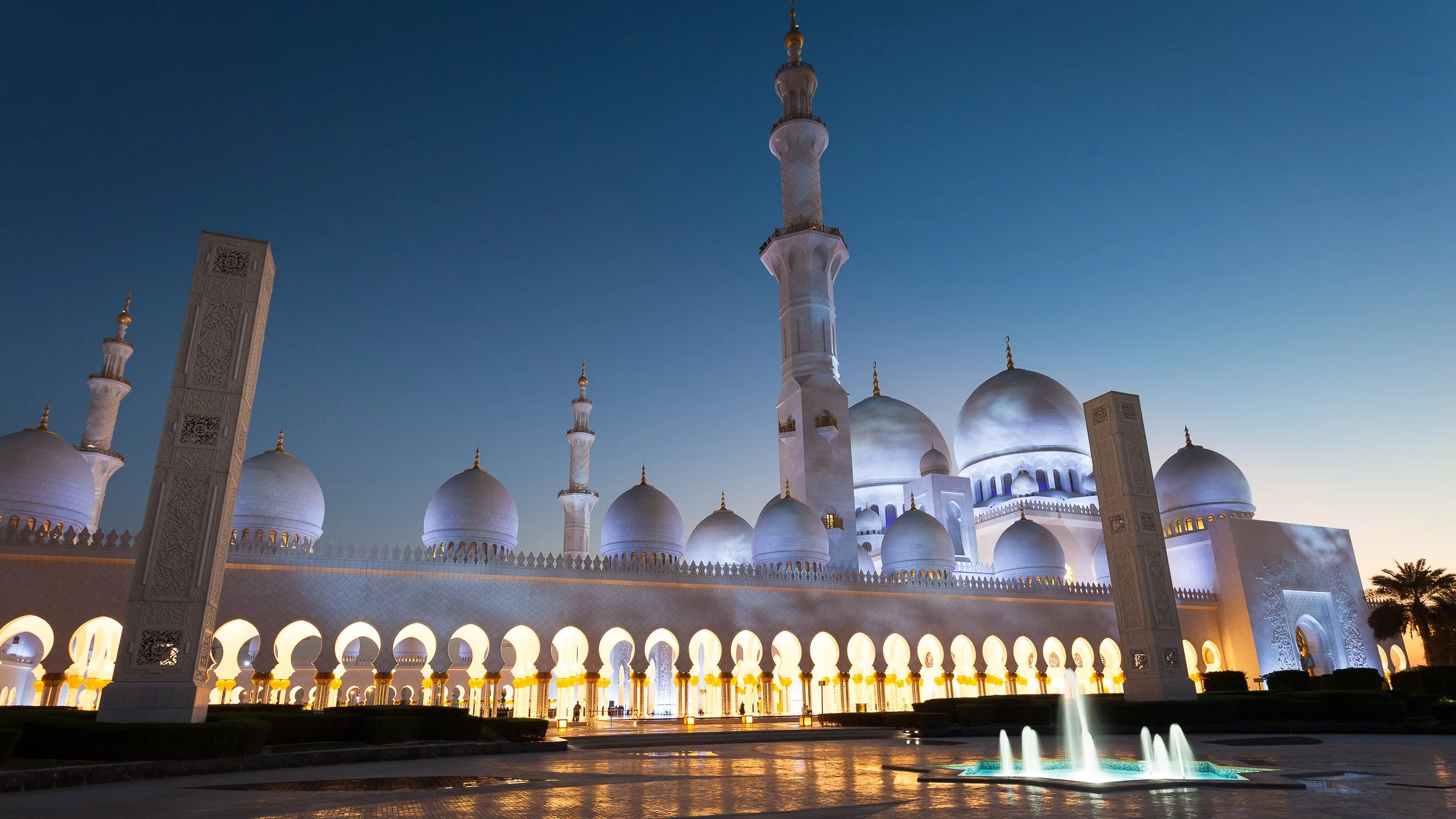 Sheikh Zayed Grand Mosque in Abu Dhabi, United Arab Emirates – majestic white domes and arches lit beautifully after dark.