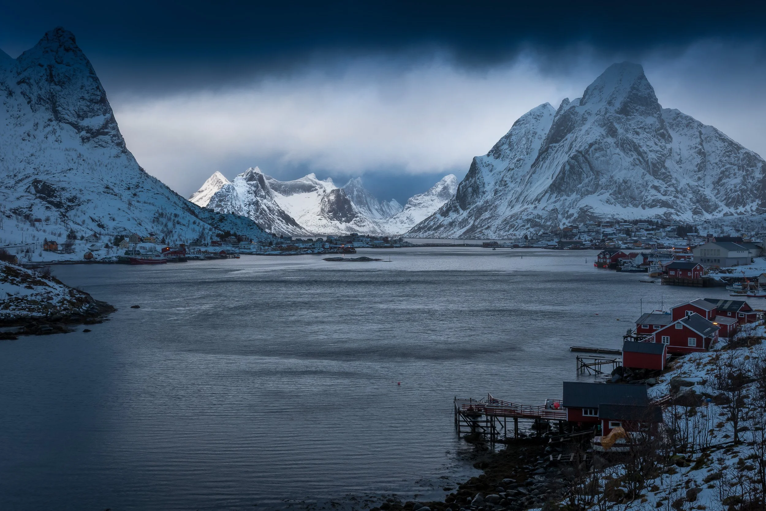 Winter lights in Reine, Lofoten Islands, Norway – blue hour glow on snow, cabins and mountains in the polar night.
