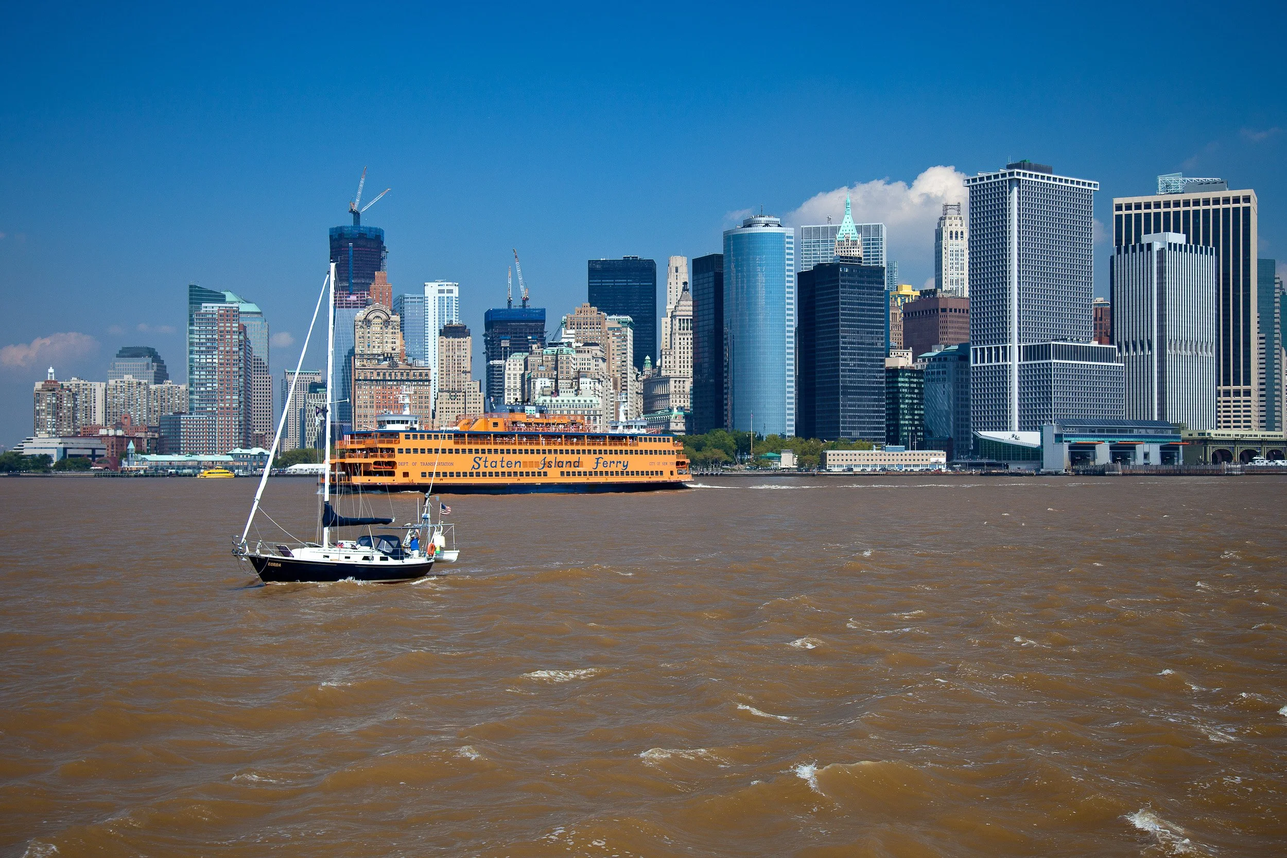 Staten Island Ferry crossing the harbour with Lower Manhattan shining beyond.