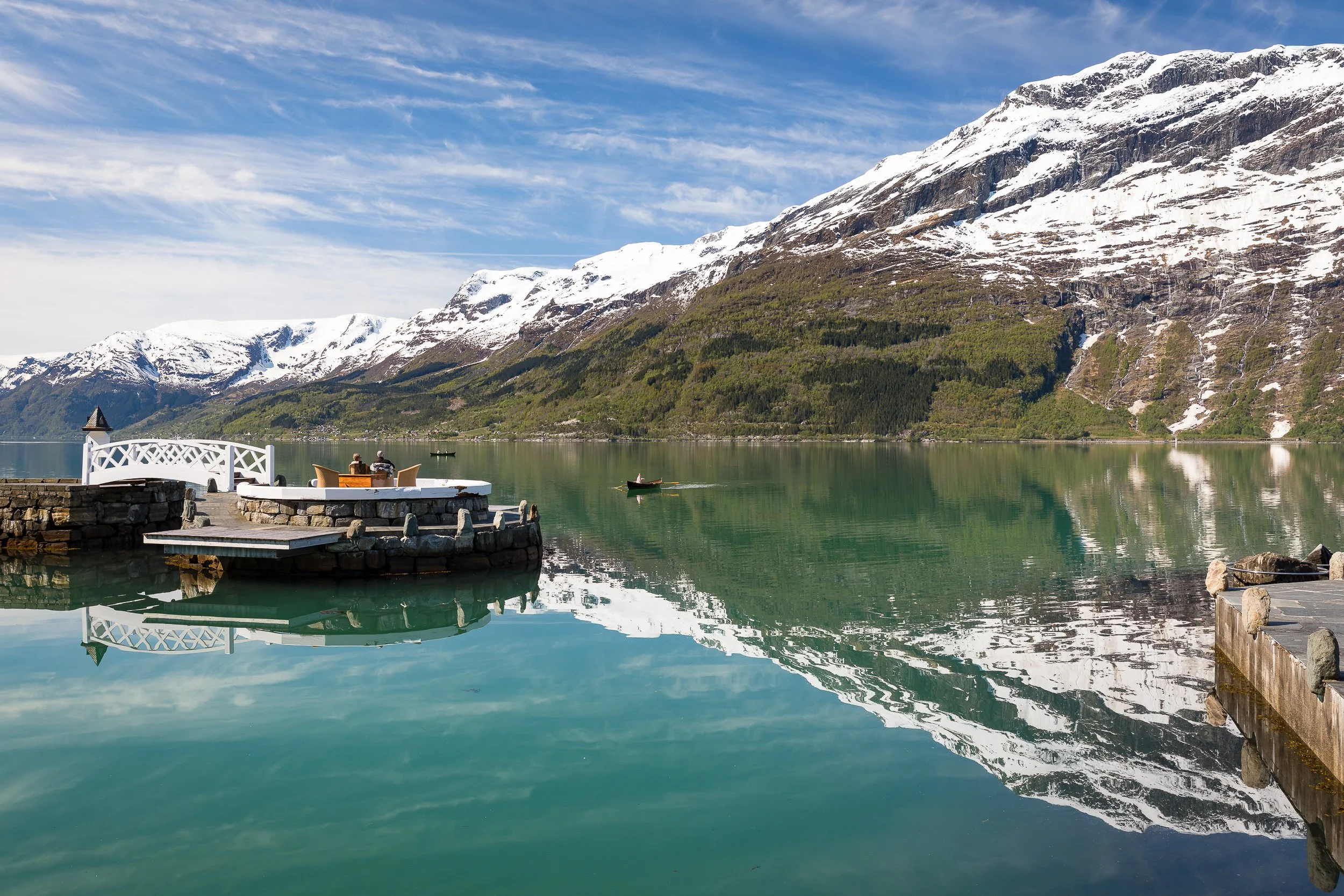 A calm morning on the Hardangerfjord at Lofthus, with snow-covered mountains reflected in green-blue water.