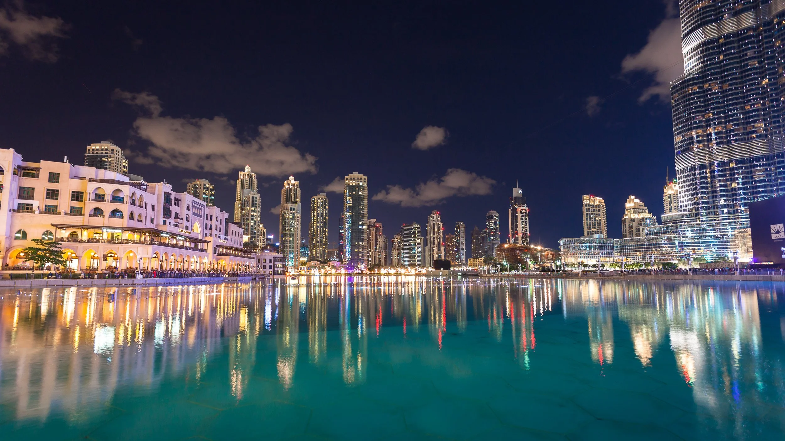 Downtown Dubai at night, United Arab Emirates – illuminated towers and waterfront buildings reflected in the still water beside Burj Khalifa.