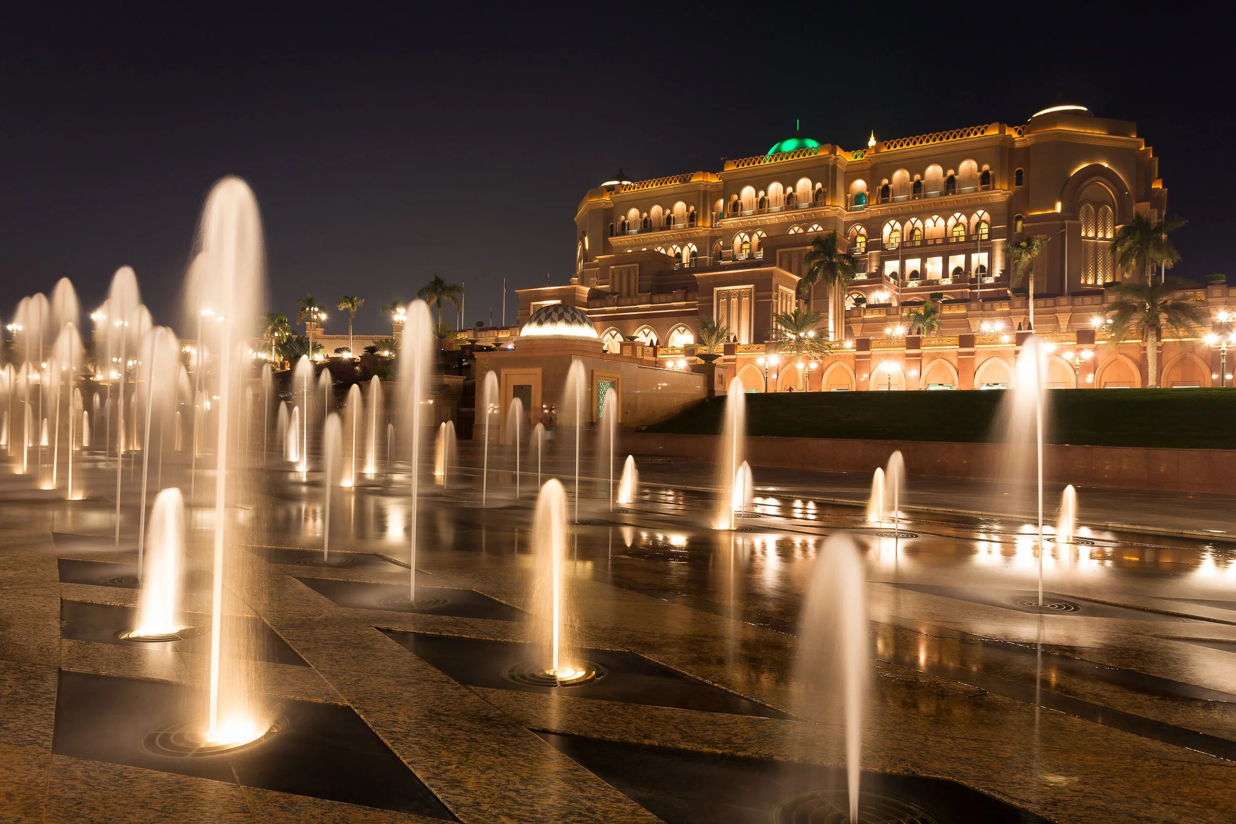 Fountains and warm palace lighting creating a cinematic evening scene in Abu Dhabi.