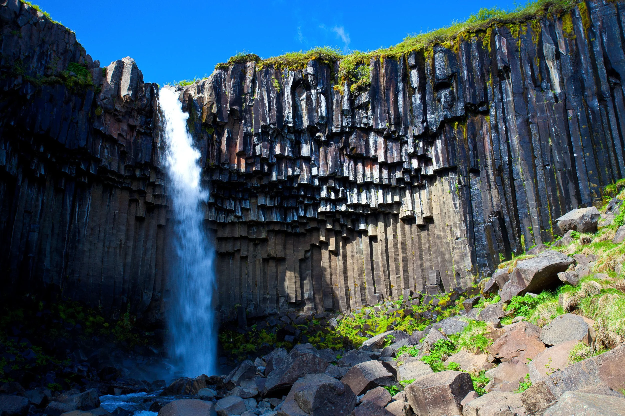 Up close, the Svartifoss waterfall drops like a white ribbon against black geometric basalt — nature’s own cathedral wall in Vatnajökull country.