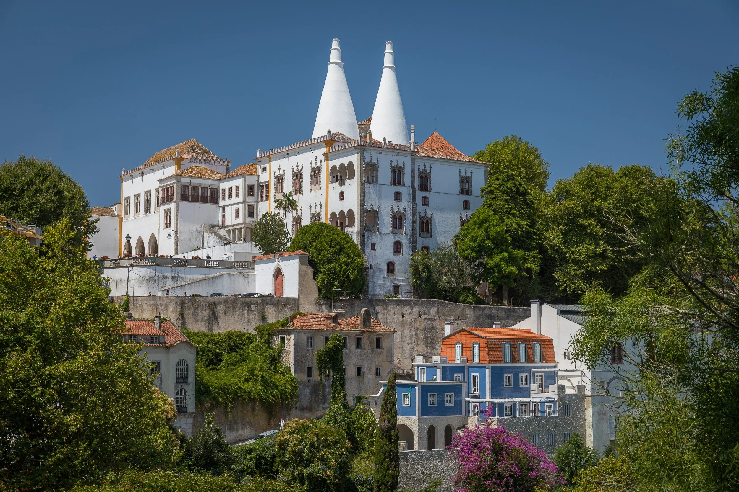 The National Palace of Sintra rises above the town, marked by its twin white chimneys and framed by trees and colourful houses.