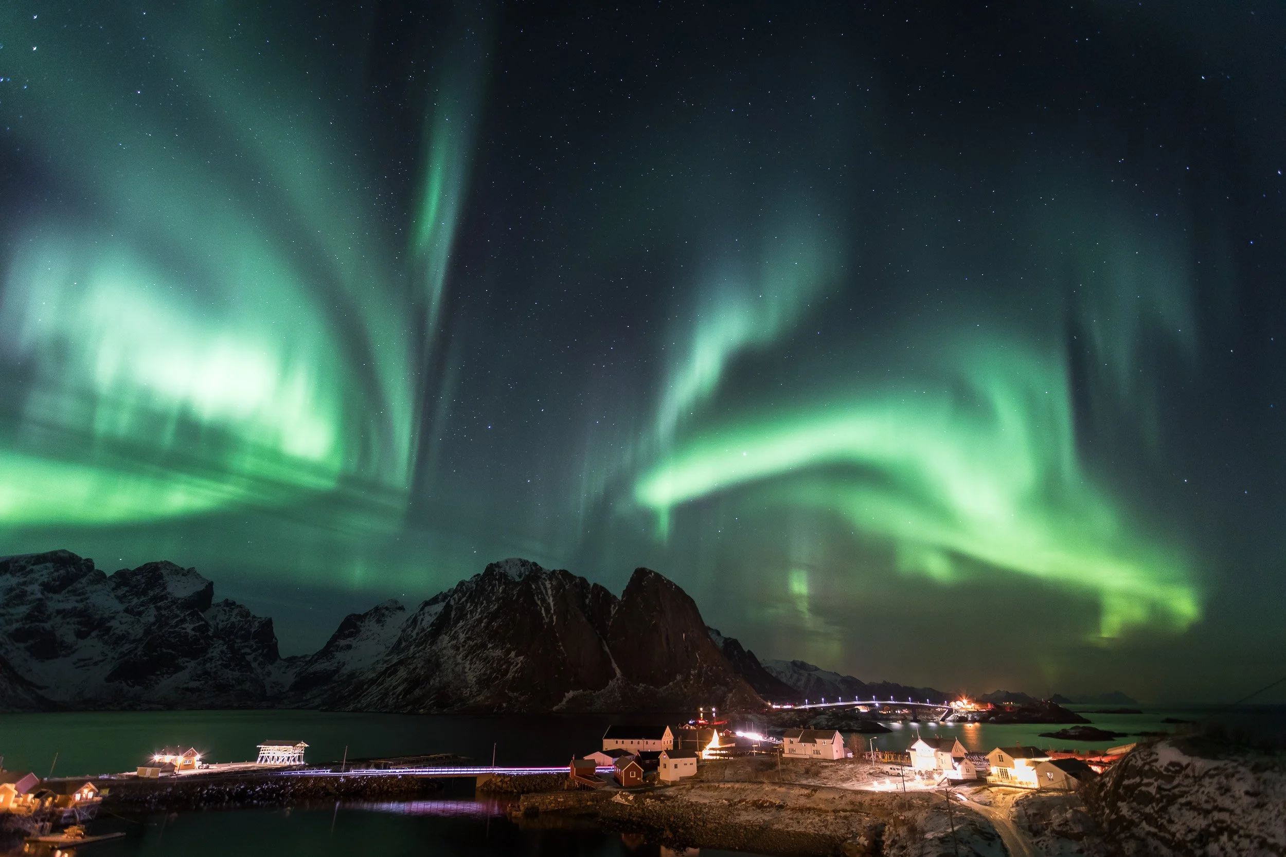 Northern lights (aurora borealis) in Reine, Lofoten Islands, Norway – starry sky and green aurora bands over the village.