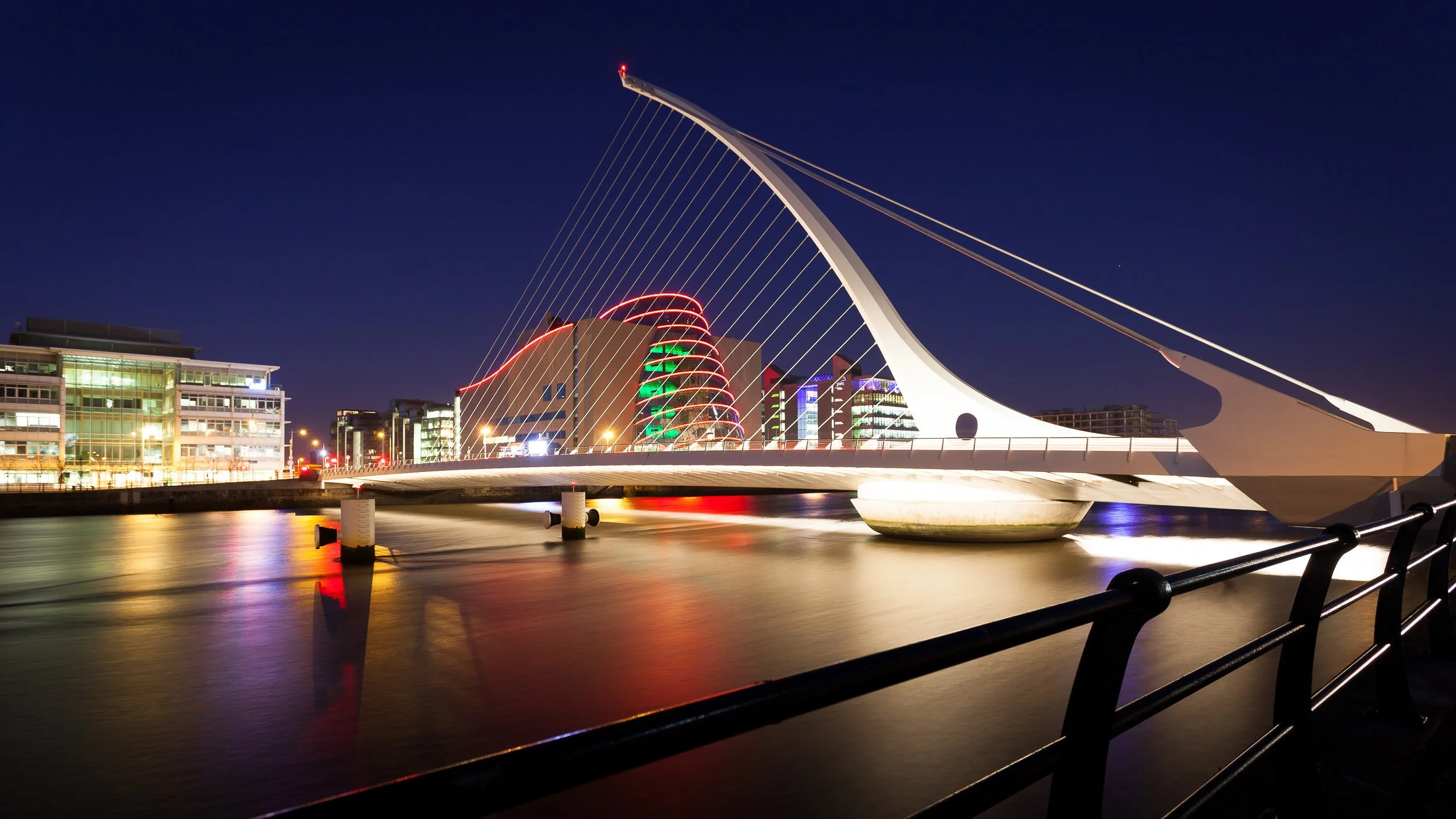 Samuel Beckett Bridge in Dublin, Ireland – modern white cable-stayed bridge lit up at night over the River Liffey.