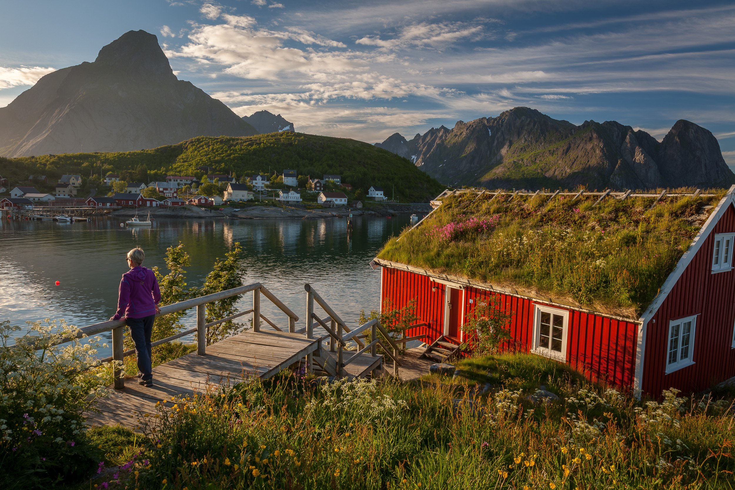 Fisherman’s cabins in Reine, Lofoten Islands, Norway – traditional red rorbuer along a calm fjord framed by sharp granite peaks.