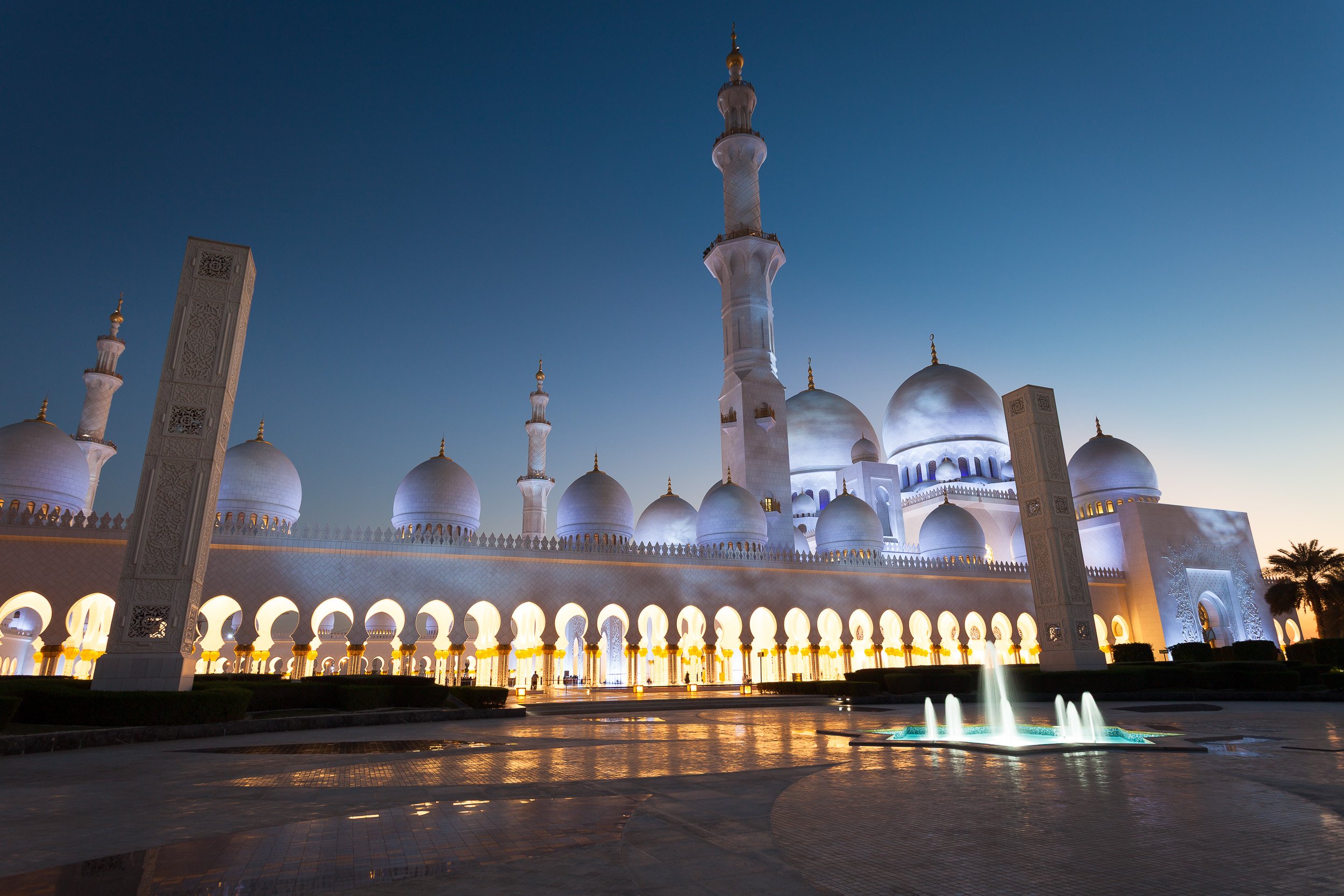 The white domes of Sheikh Zayed Grand Mosque glowing at the edge of evening, Abu Dhabi.