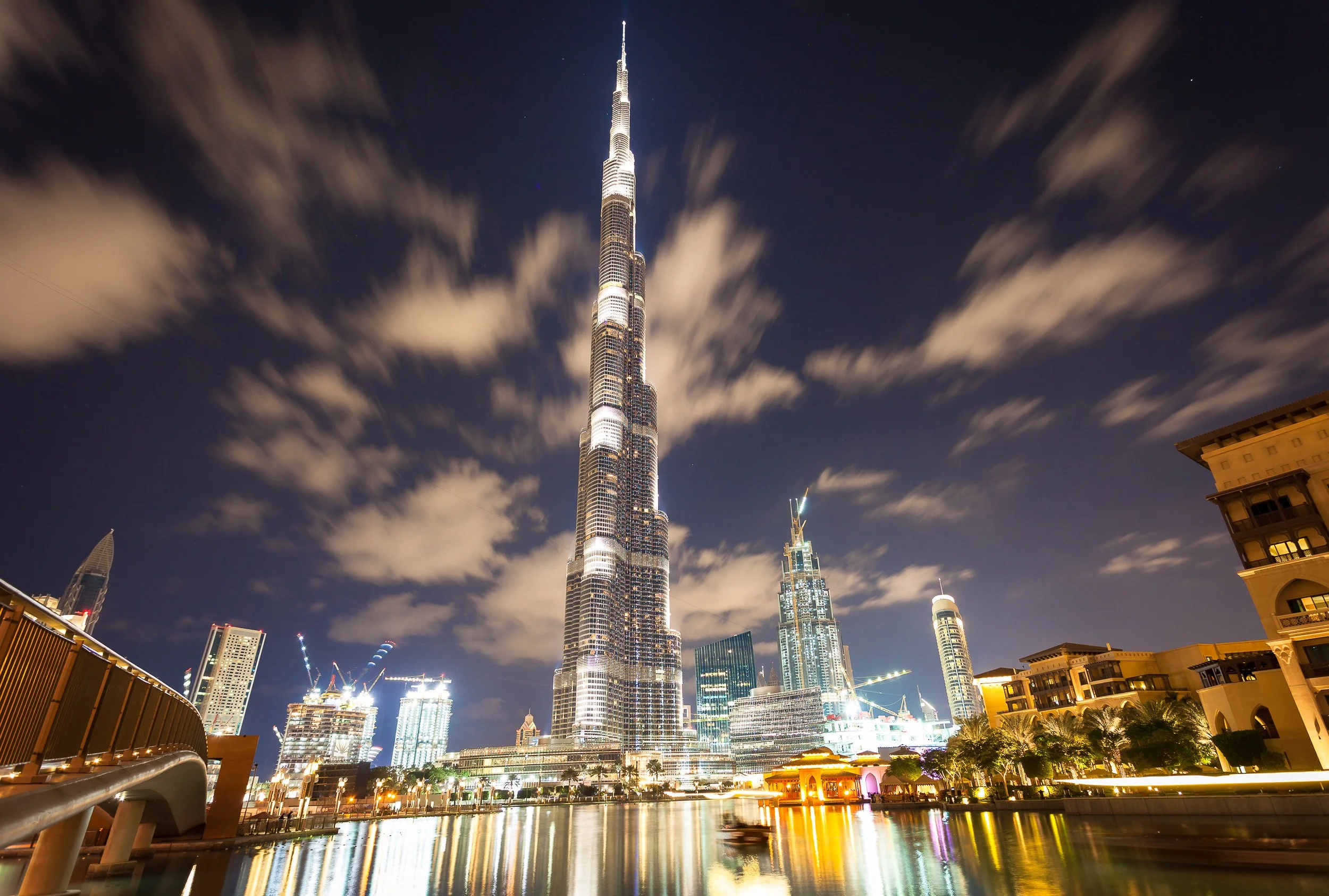 Burj Khalifa soaring into drifting clouds above Downtown Dubai after dark.