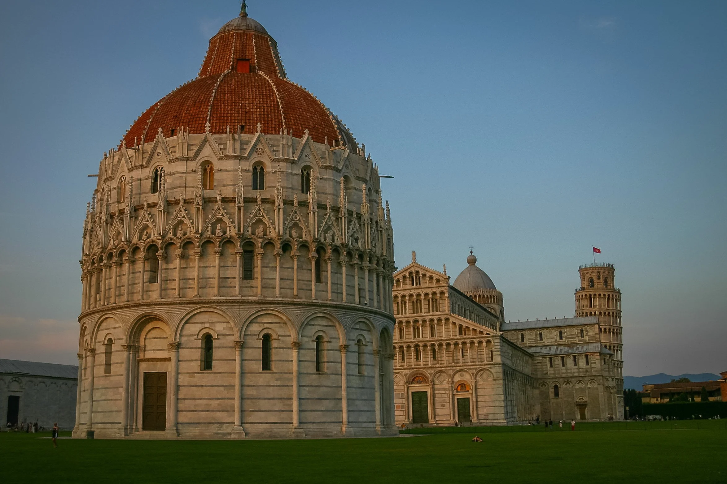 The Baptistery, Cathedral and Leaning Tower in Pisa at dusk, standing in quiet evening light on the Piazza dei Miracoli.