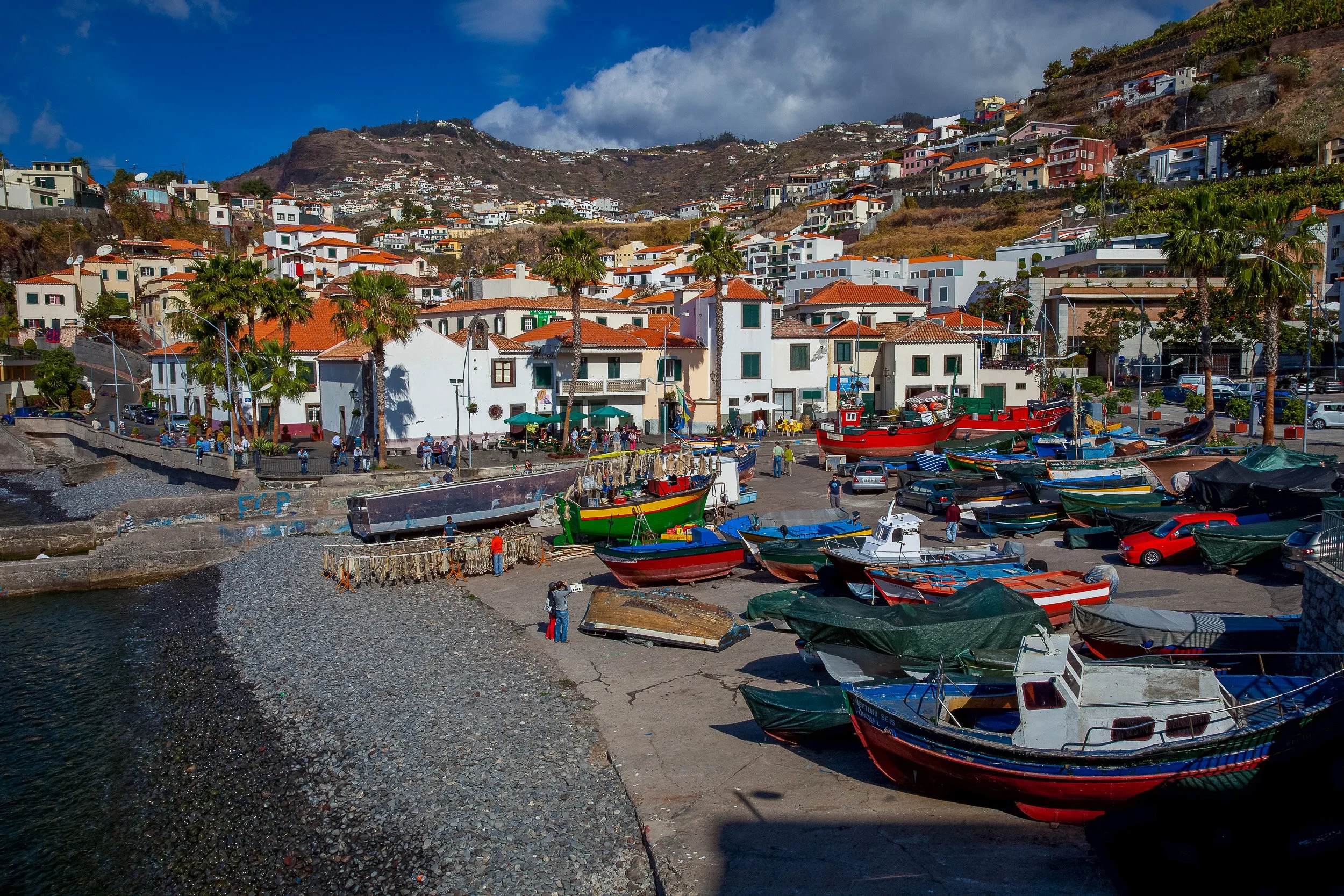 Fishing boats, red-tiled roofs and steep cultivated hillsides shape the harbour of Câmara de Lobos, a compact village pressed between the Atlantic and the mountains.