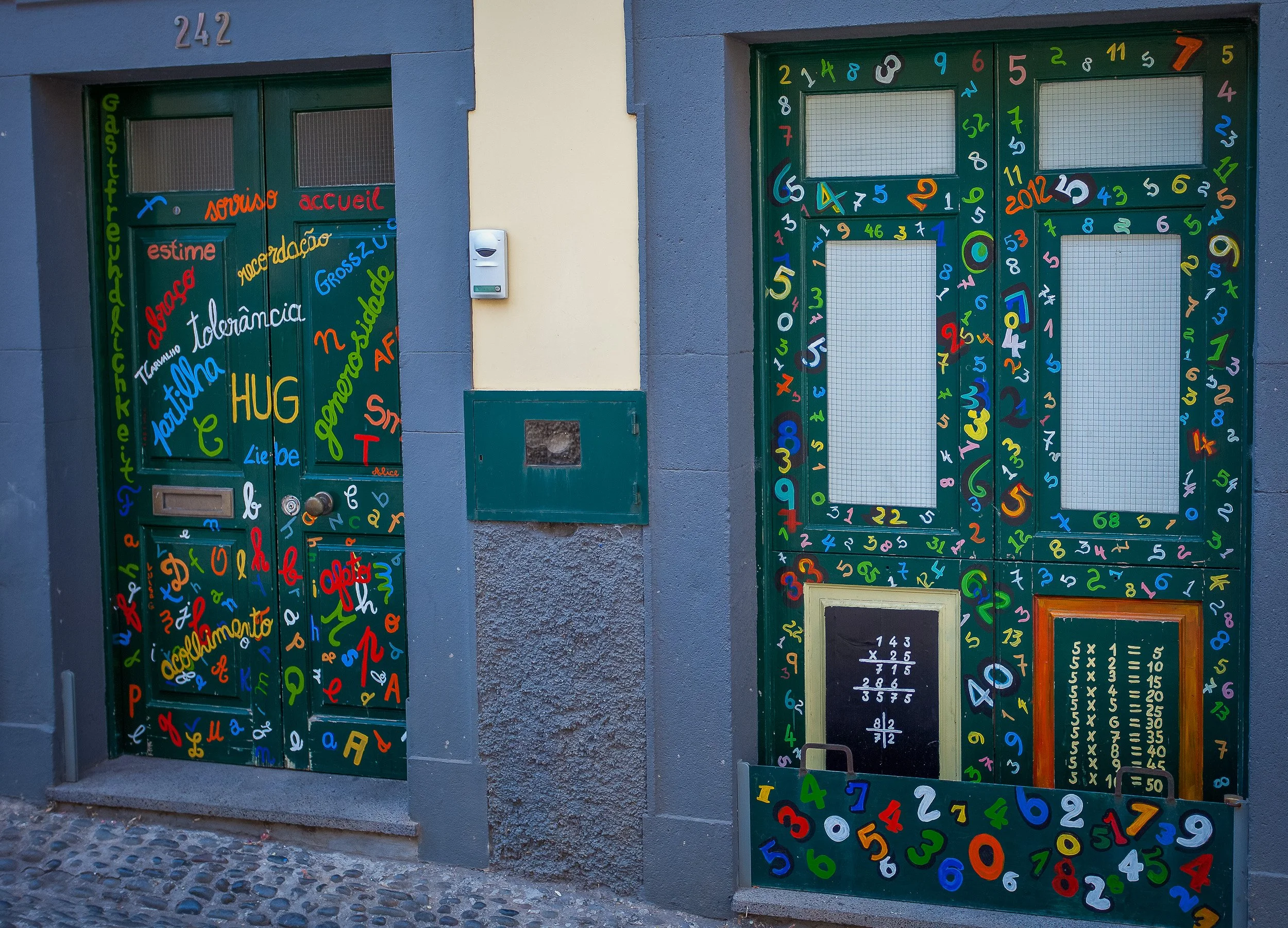 Painted doors in Funchal’s old town, covered with letters, numbers and fragments of colour that turn a quiet street façade into a playful urban detail.