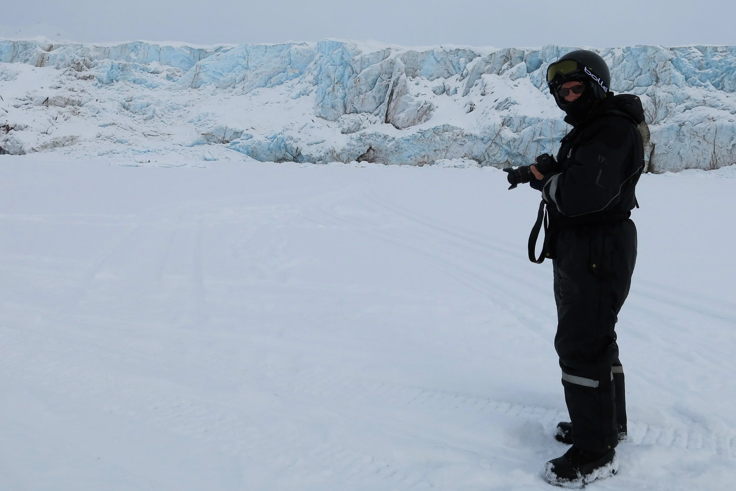 A rare glimpse of the photographer on the frozen fjord, standing before a glacier wall during a winter stop.