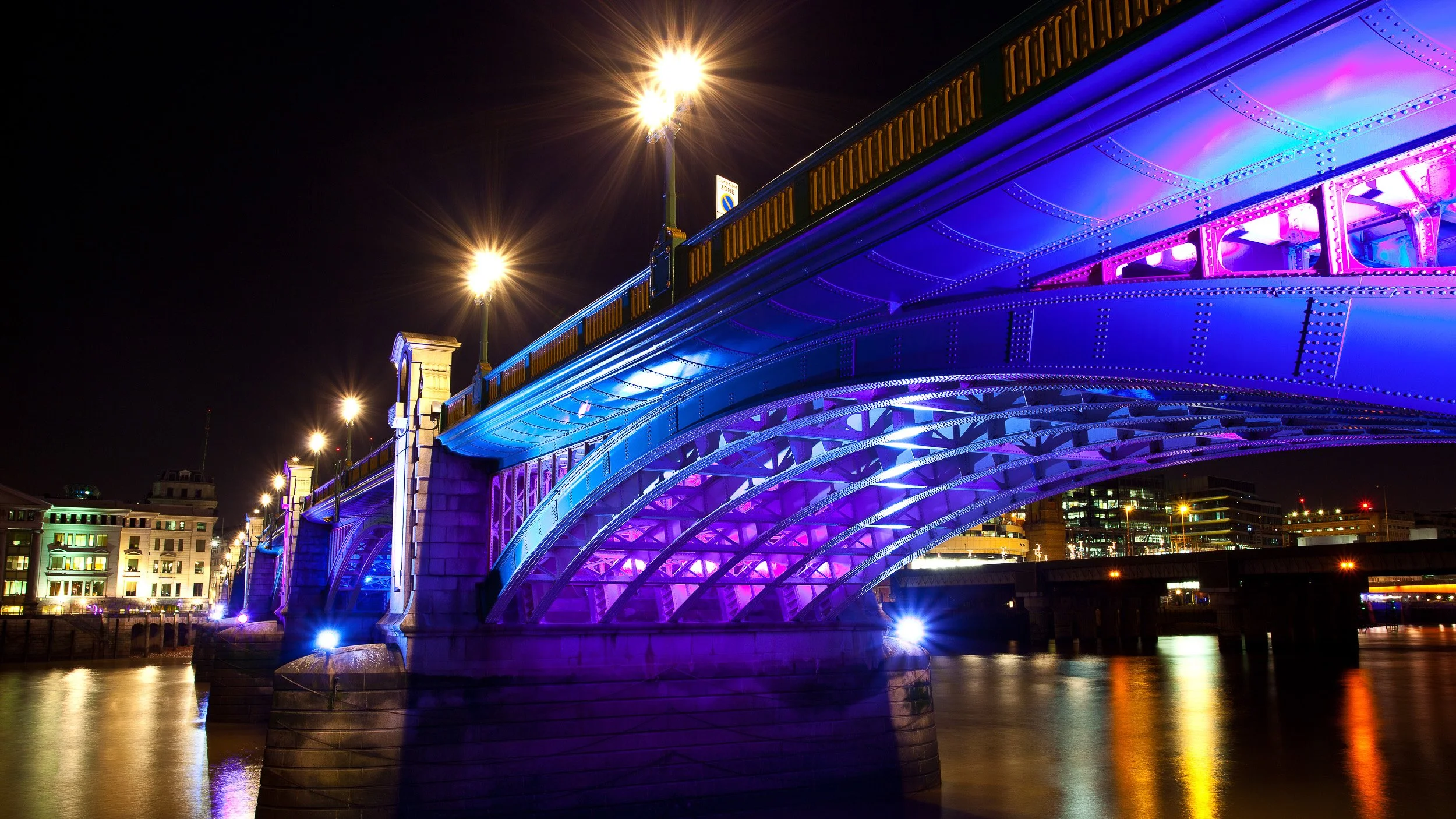 Southwark Bridge in London, UK – night view with the River Thames reflecting city lights and illuminated arches.