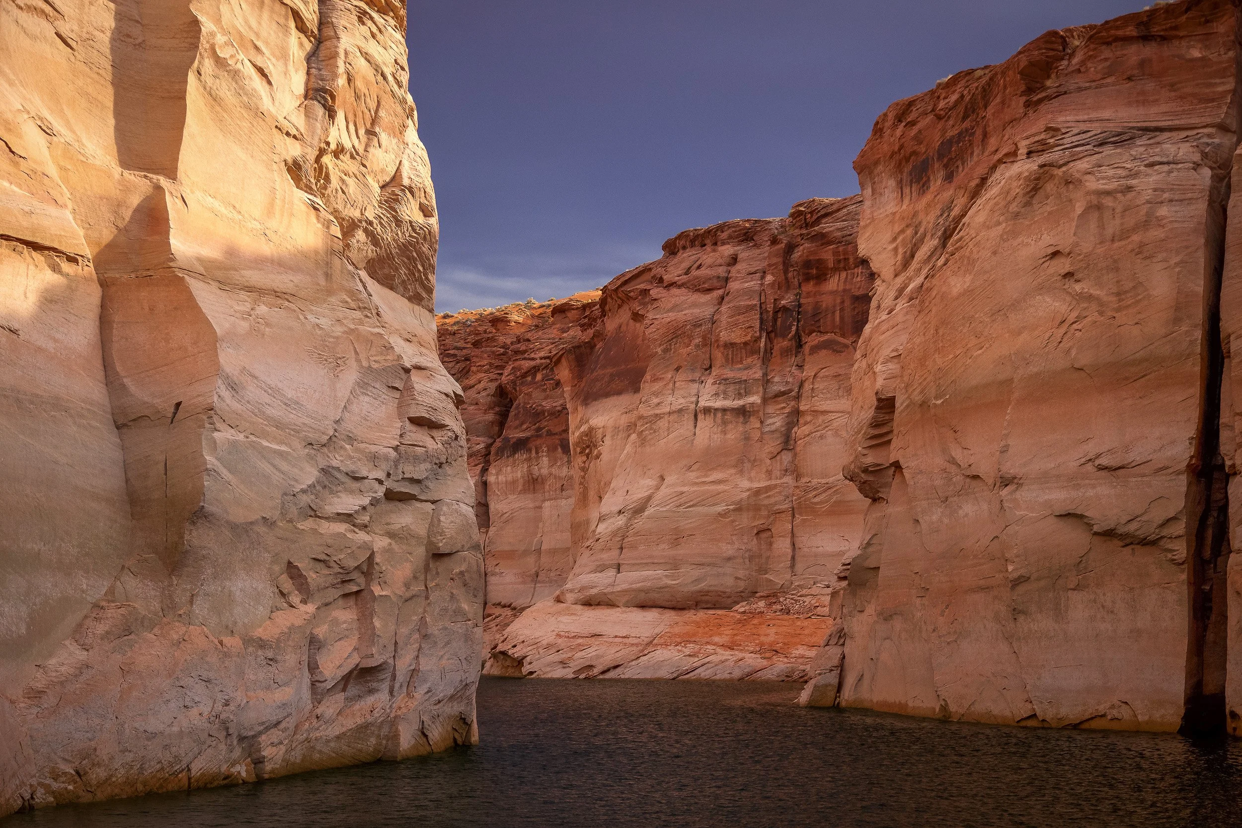 Narrow sandstone walls reflected in the calm waters of Lake Powell, Arizona.