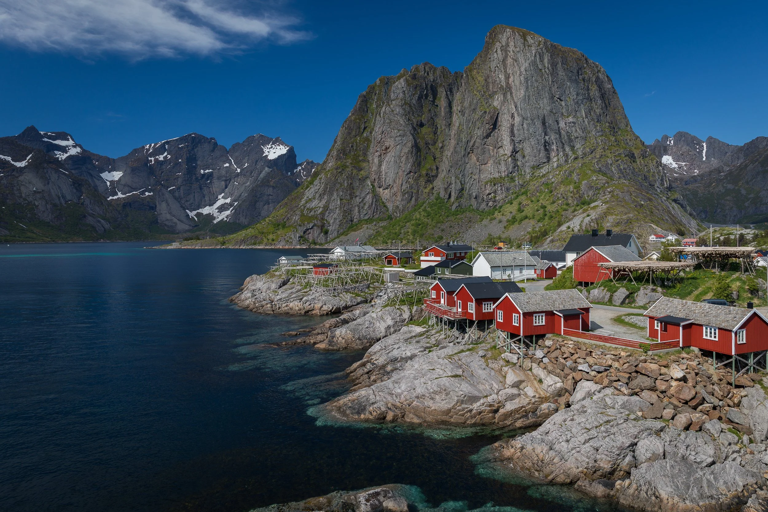 Fisherman’s cabins at Hamnøy, Lofoten Islands, Norway – classic red houses on stilts beneath towering cliffs and a narrow bridge.