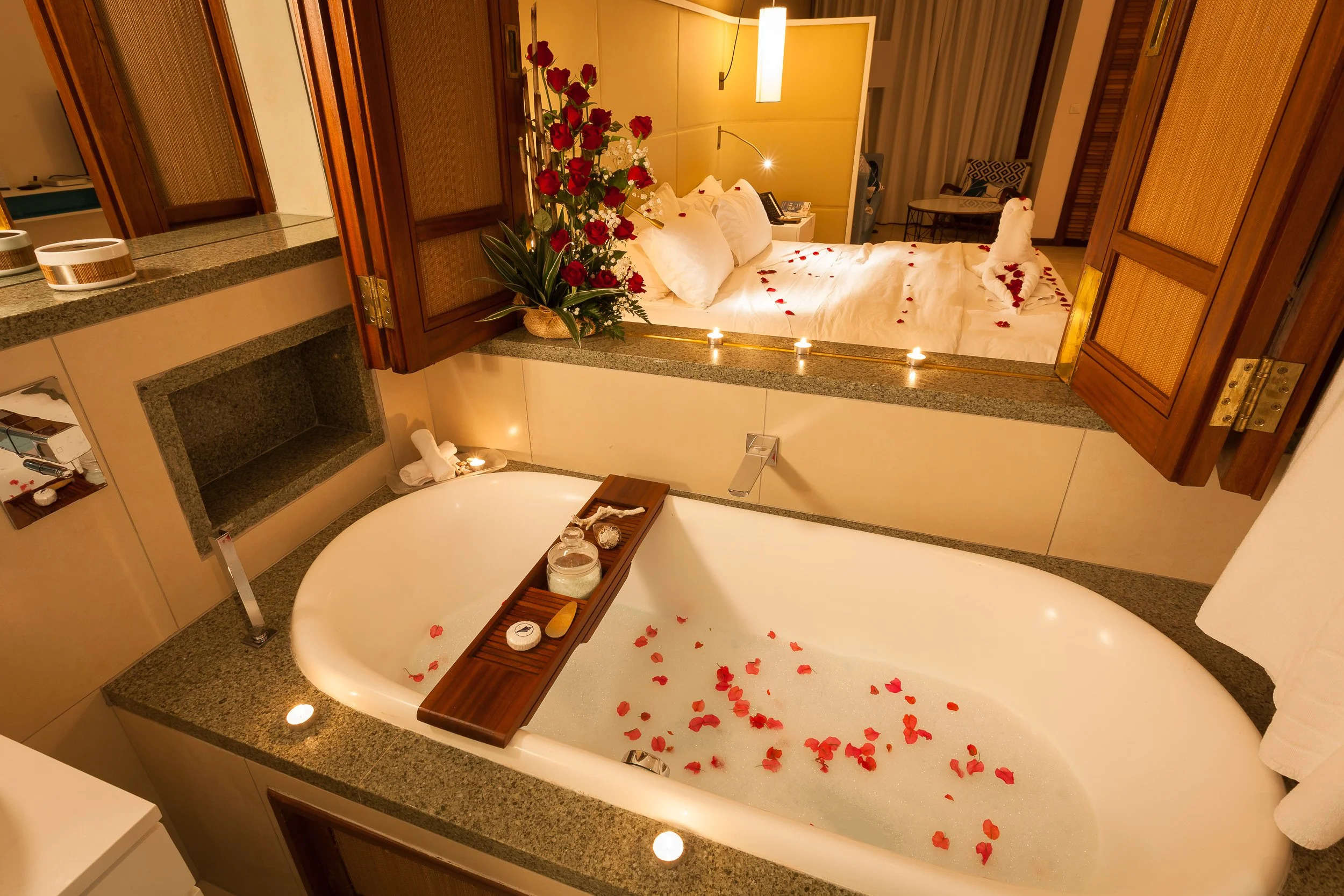 Romantic turn-down at Constance Belle Mare Plage, with a bubble bath sprinkled with petals and a bed in the next room dressed in rose hearts and candlelight
