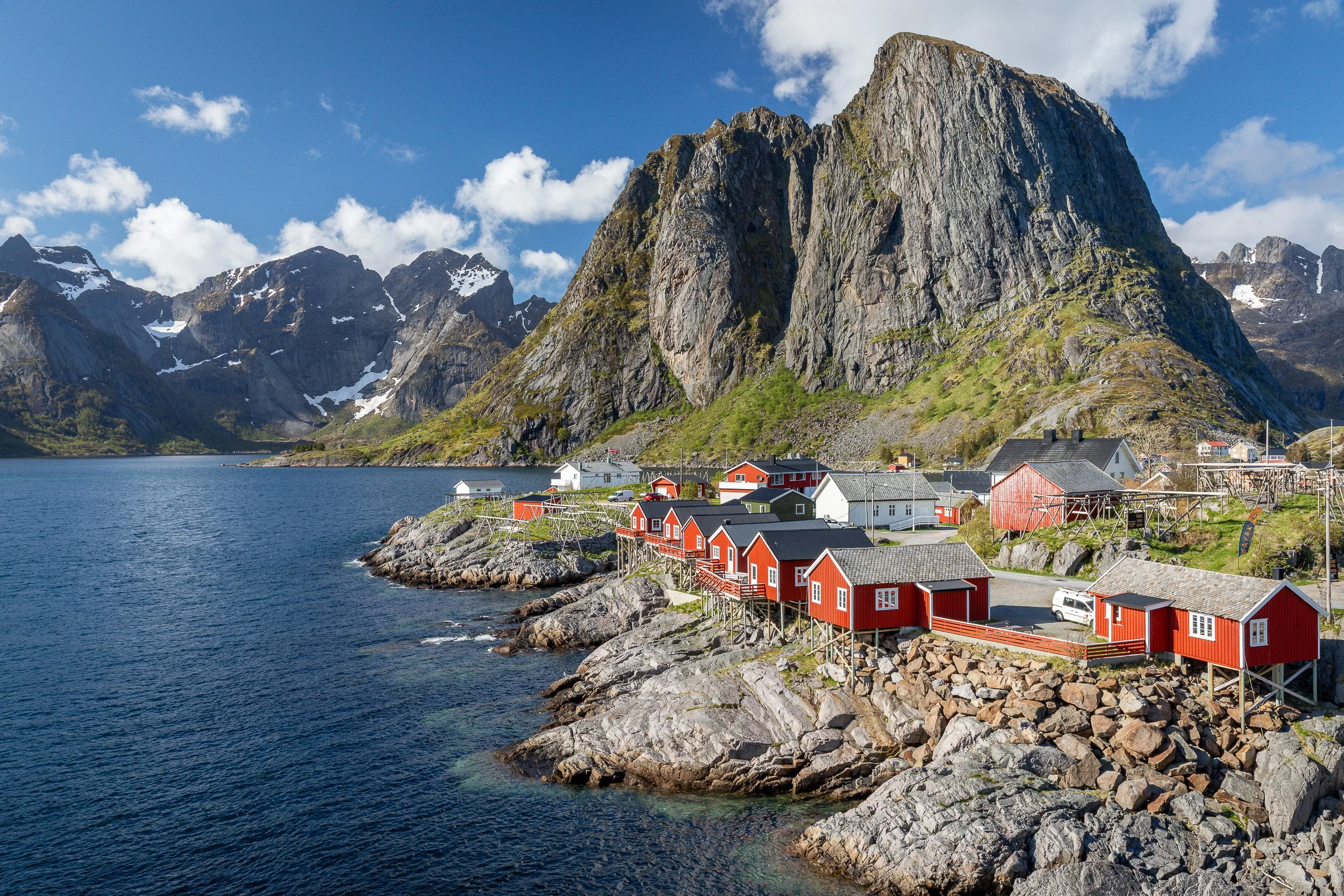 Fisherman’s cabins in Hamnøy, Lofoten Islands, Norway – red rorbuer on rocky shoreline beneath dramatic mountain walls.