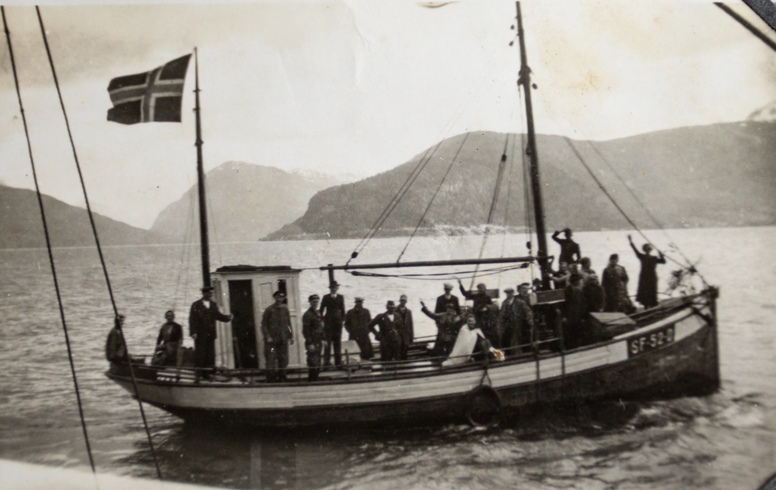 Kutteren «Hovdenes» SF-52-D med et bryllupsfølge om bord. Bildet er etter all sannsynlighet tatt ved Blaksetnausta i Innvikfjorden i 1938. De mange passasjerene står tett samlet på dekk, flere vinker mot fotografen, mens kvinnen i lys kjole midtskips