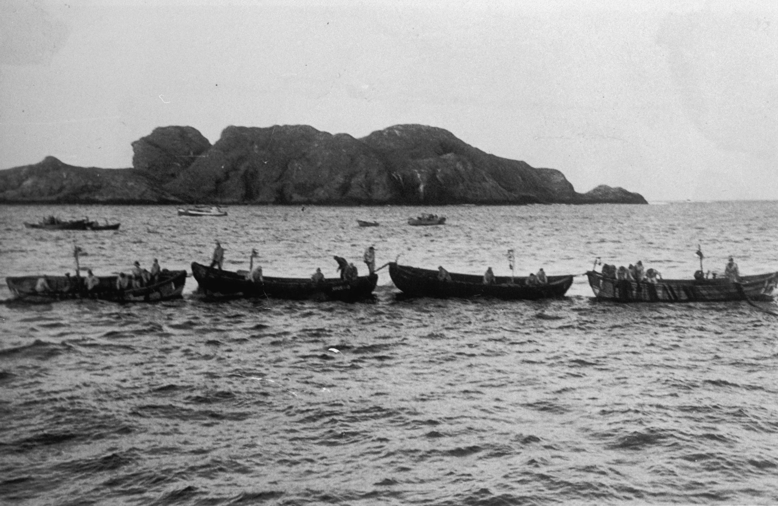 Historisk svart-hvittbilde av sildfiske ved Klovningen vest for Husevågøy, med dorryer langs nota.