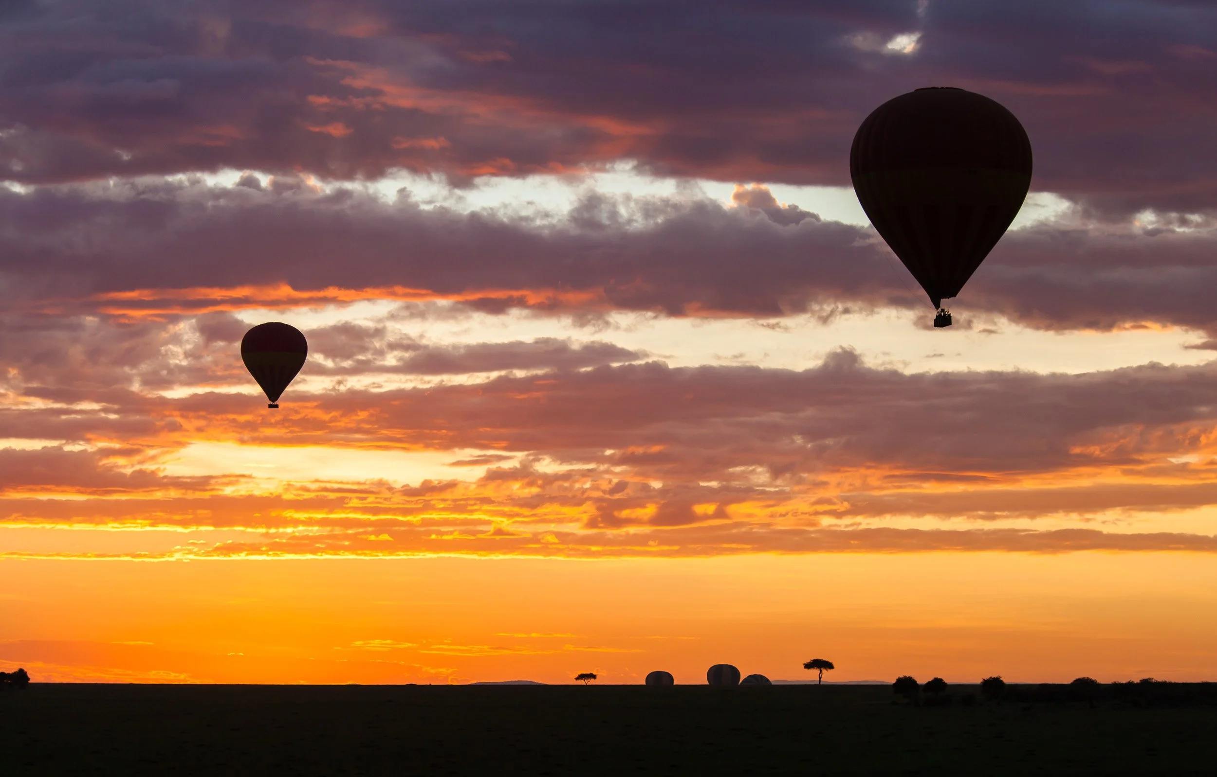 Hot air balloon in Maasai Mara National Reserve, Kenya – basket and burner glowing above the endless savanna.