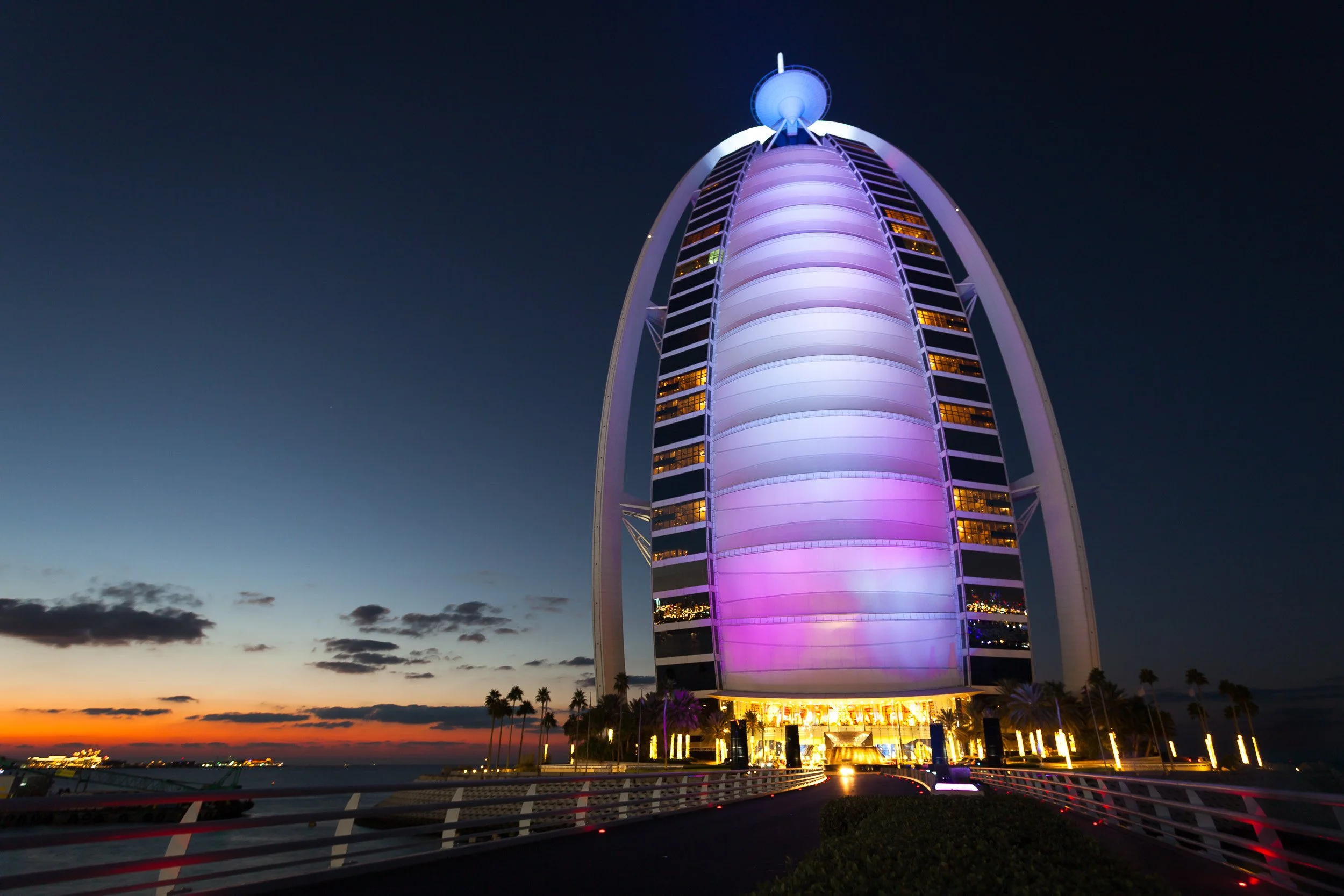 Burj Al Arab illuminated at dusk, rising like a sail above the Arabian Gulf.