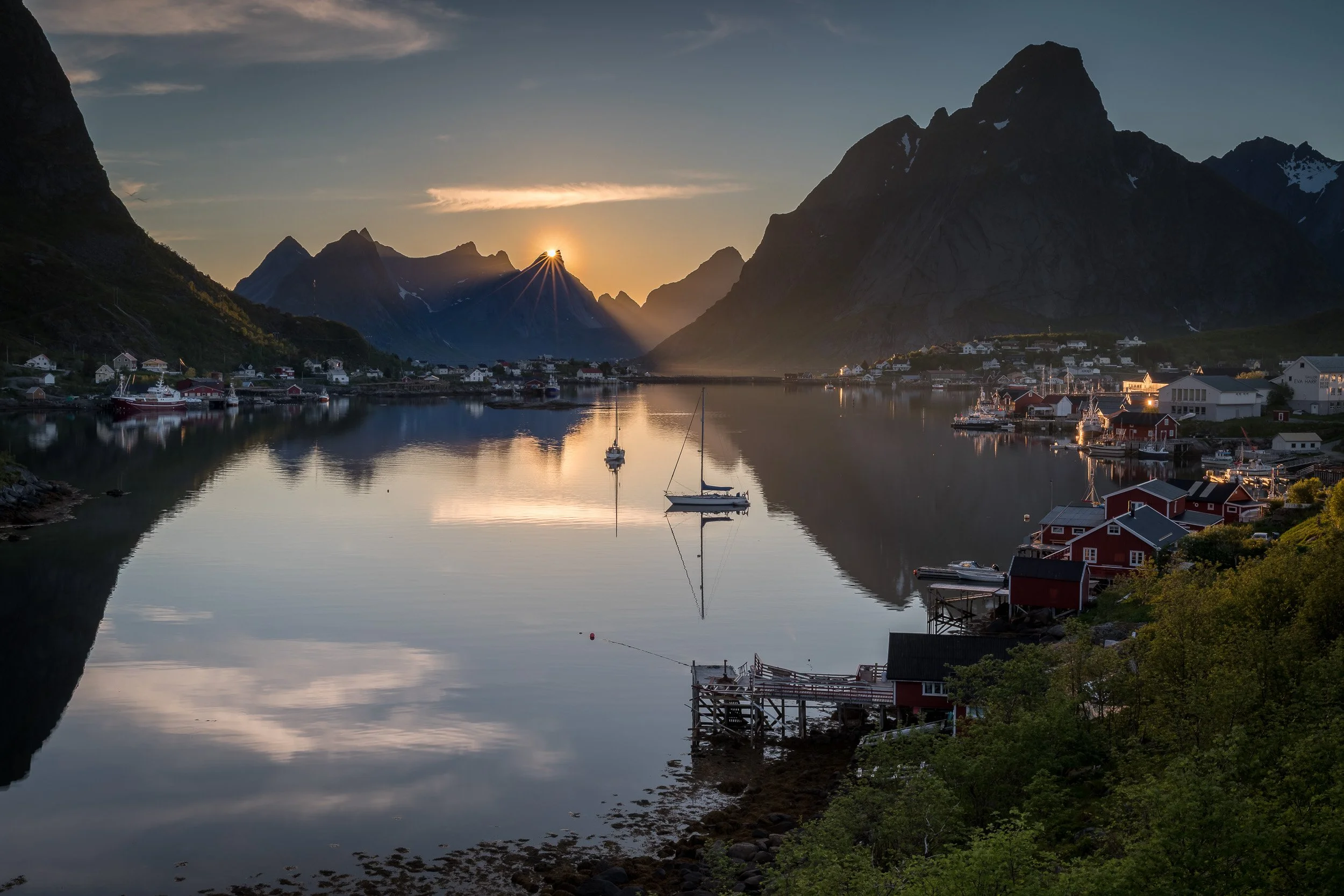 Midnight sun in Reine, Lofoten Islands, Norway – orange Arctic light skimming the horizon over calm water and islands.