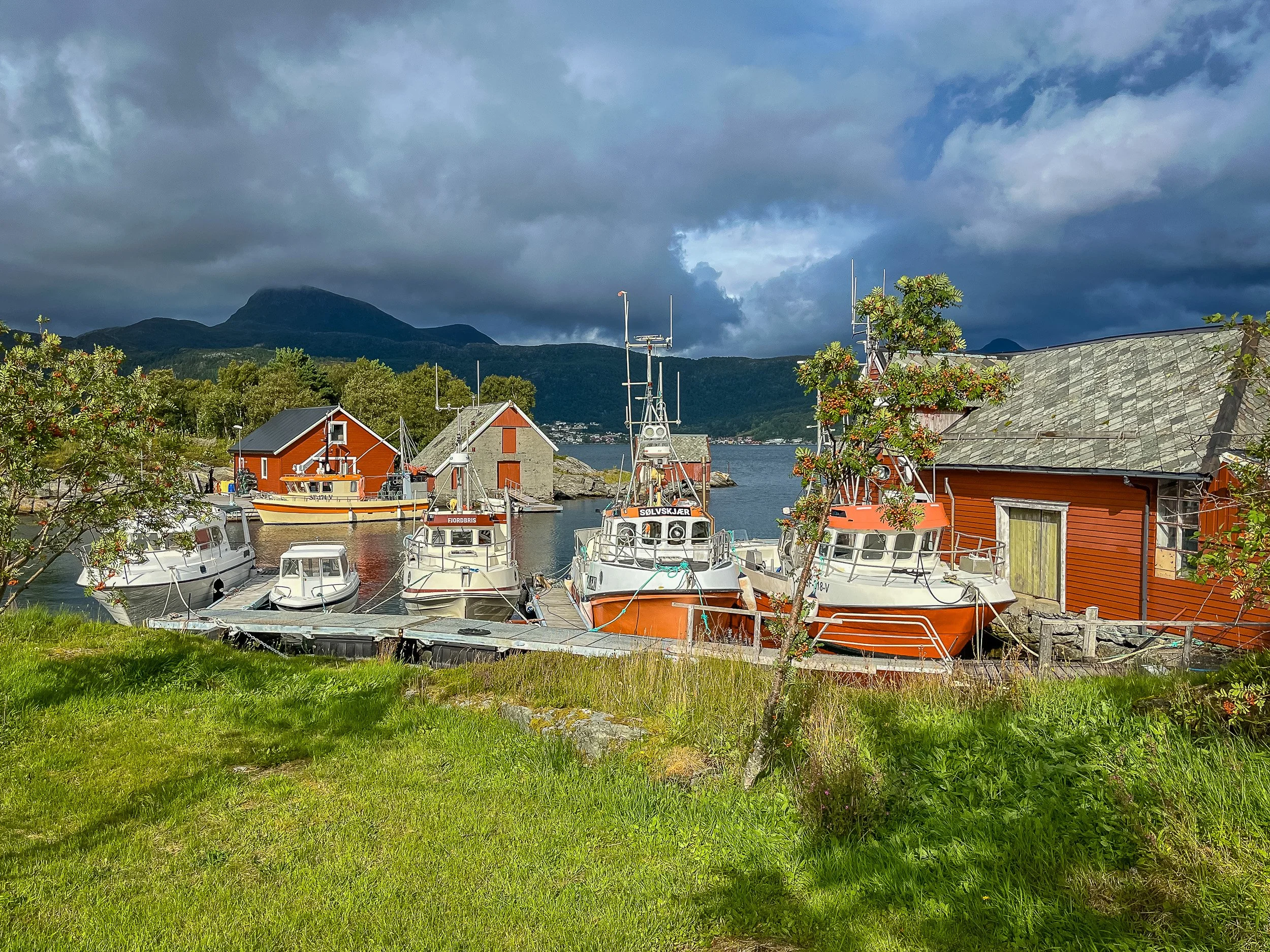 Båthavnen i Husevåg på Husevågøy – lune brygger, småbåter og utsikt mot fjord og fjell i Nordfjord-området på Vestlandet.