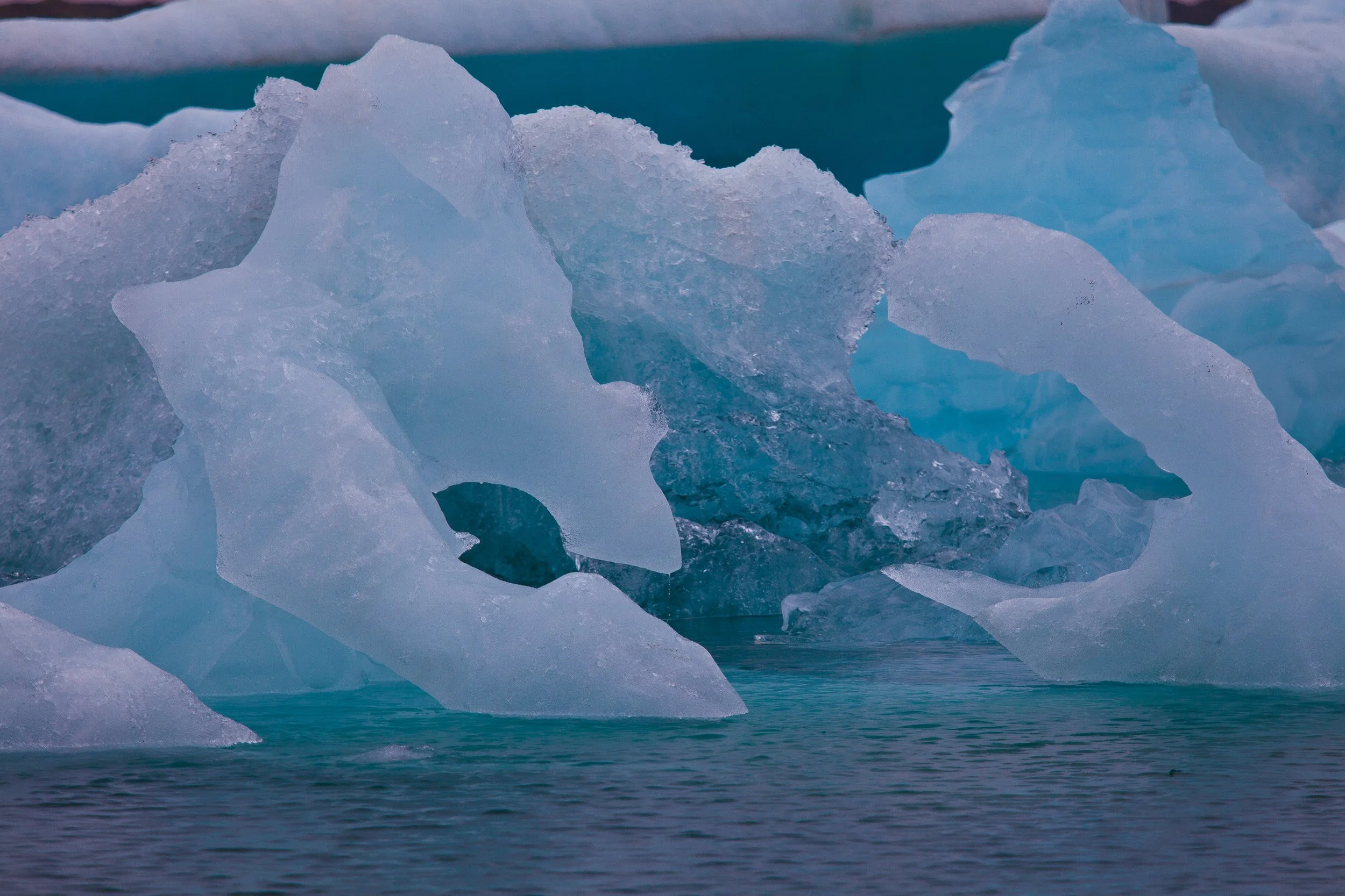 Jökulsárlón Glacier Lagoon, Iceland — a sculpted iceberg glows turquoise where meltwater has carved sharp edges and arches.