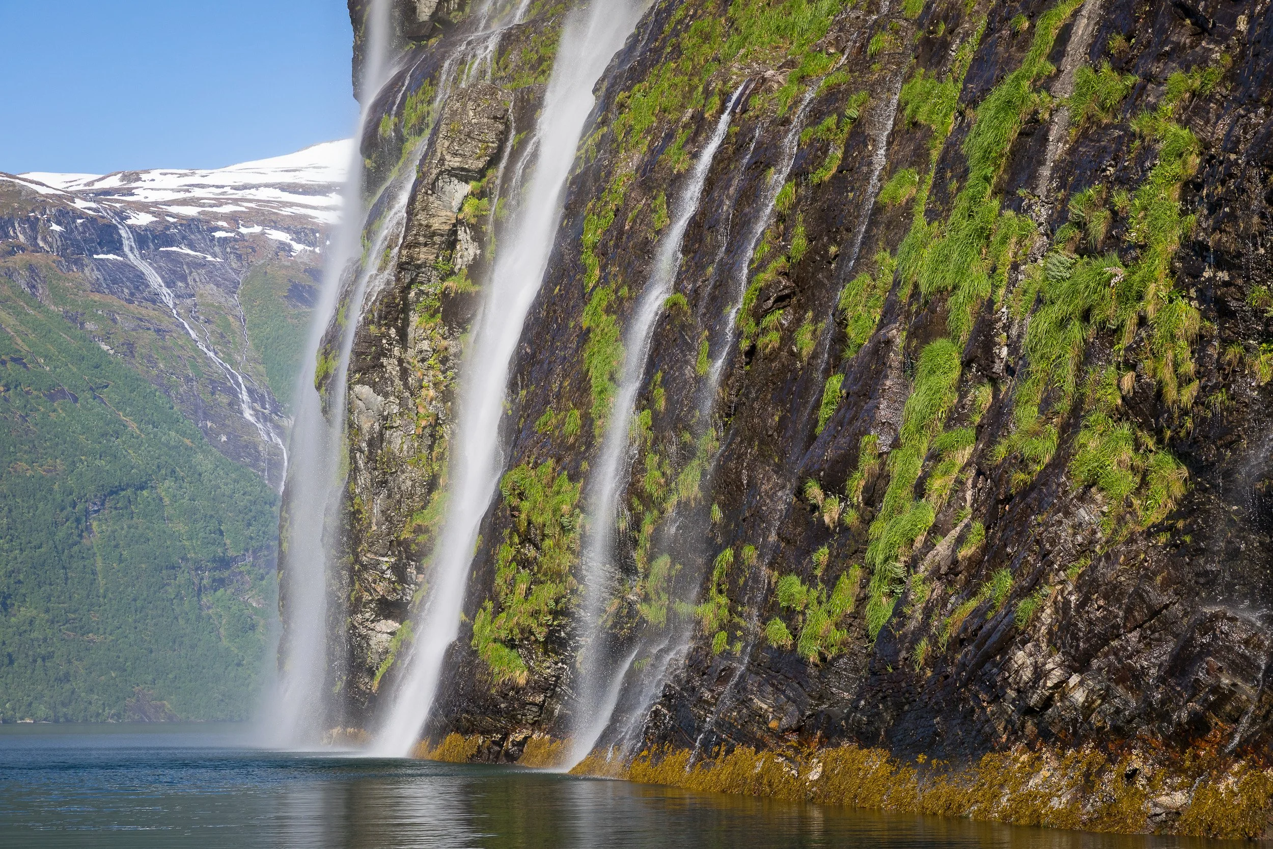The famous Seven Sisters (De syv søstre) in Geirangerfjorden, streaming down the rock face like white ribbons in the sun.