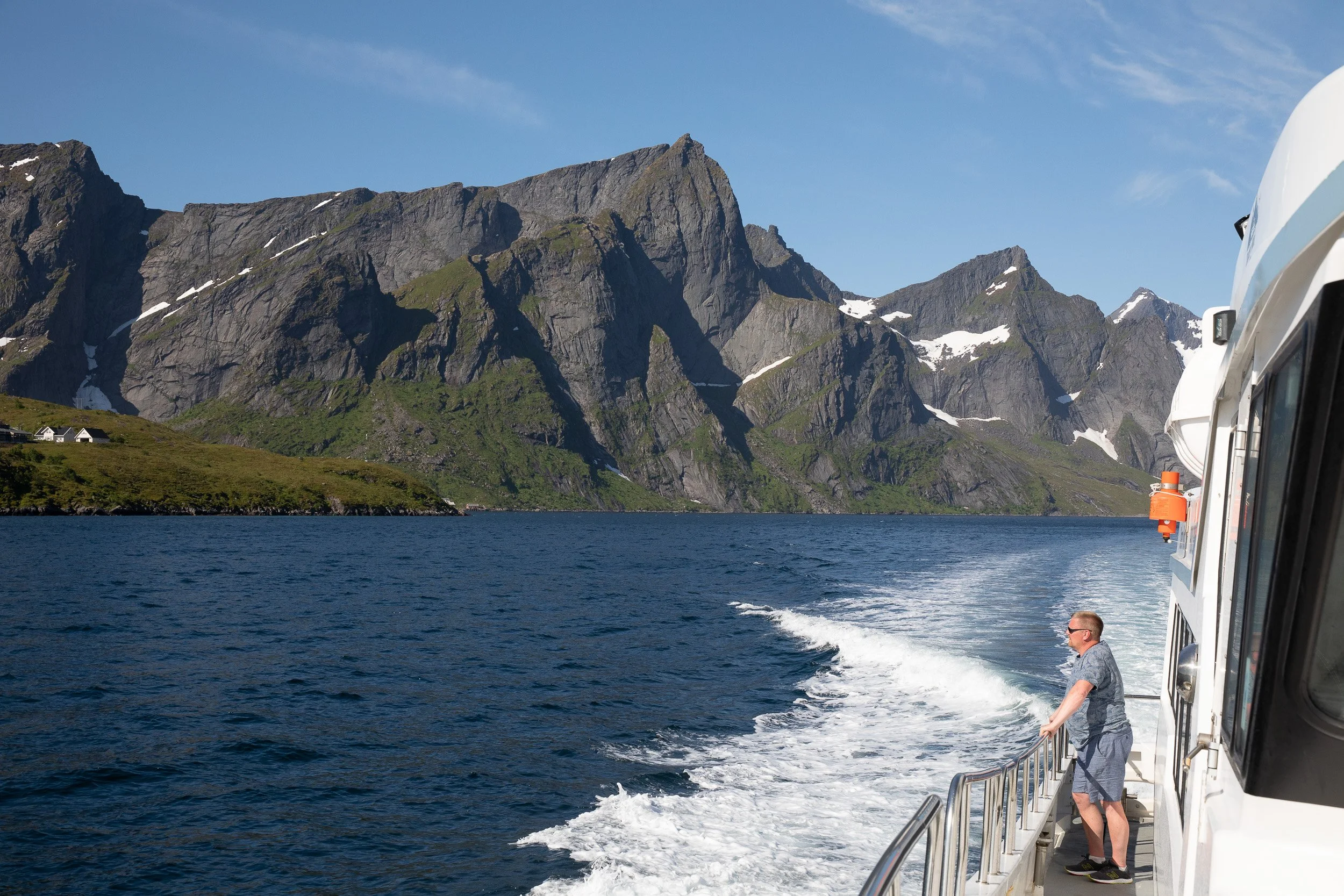 Kjerkfjorden, Lofoten — travelling by boat between sharp peaks and dark water, with the wake carving a bright line through the fjord.