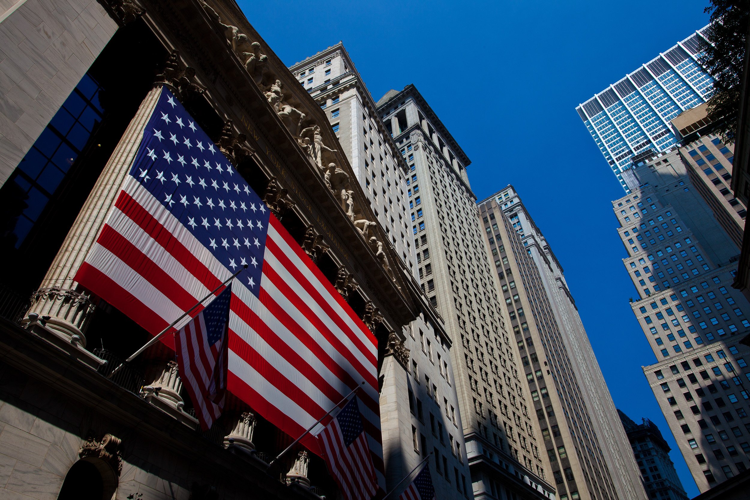 A proud Stars and Stripes hanging from the New York Stock Exchange beneath Wall Street’s stone façades.