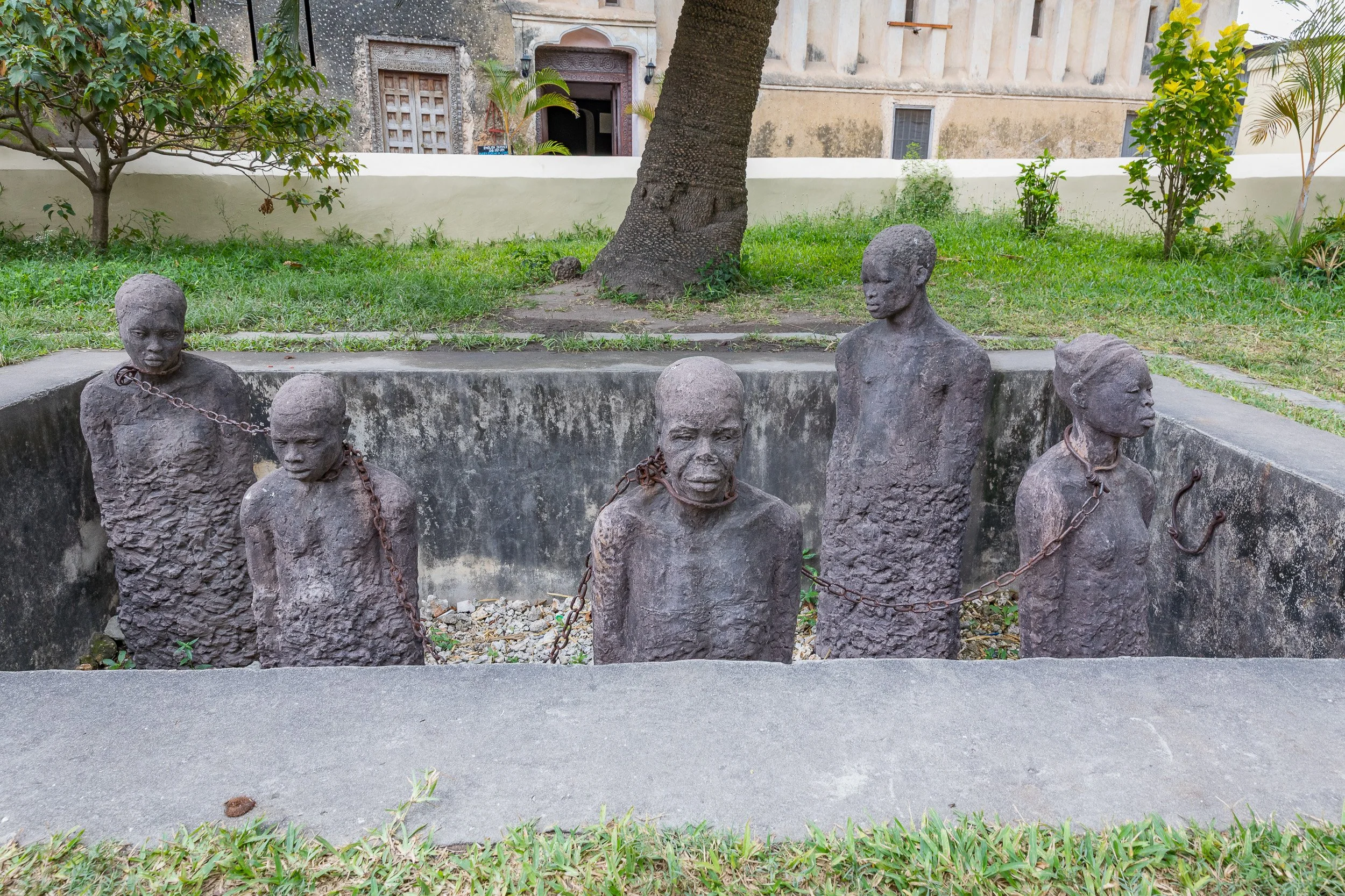 Memorial to the victims of the East African slave trade beside the Anglican Cathedral in Stone Town, Zanzibar – life-size stone figures in a sunken pit inviting quiet reflection.