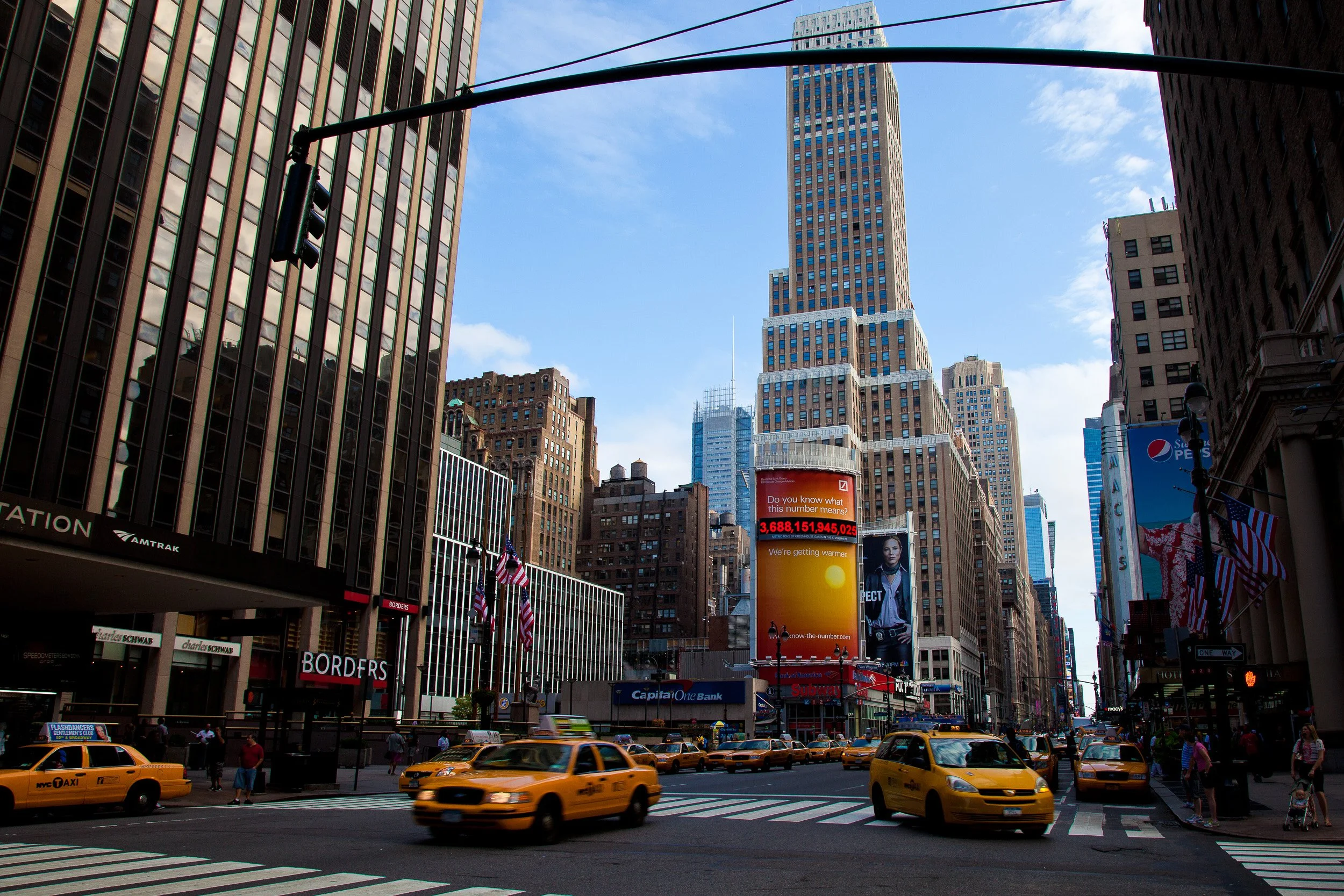 Yellow cabs sweeping through Midtown beneath tall façades and a clear Manhattan sky.
