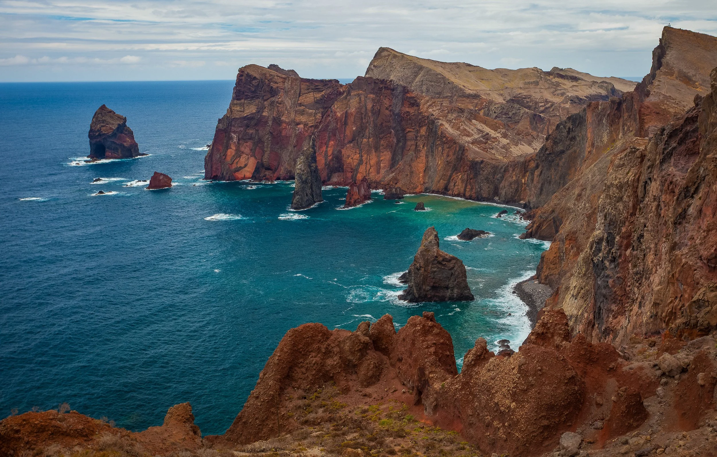 The volcanic headland of Ponta de São Lourenço, with red and ochre cliffs, sea stacks and turquoise water revealing Madeira’s drier eastern edge.