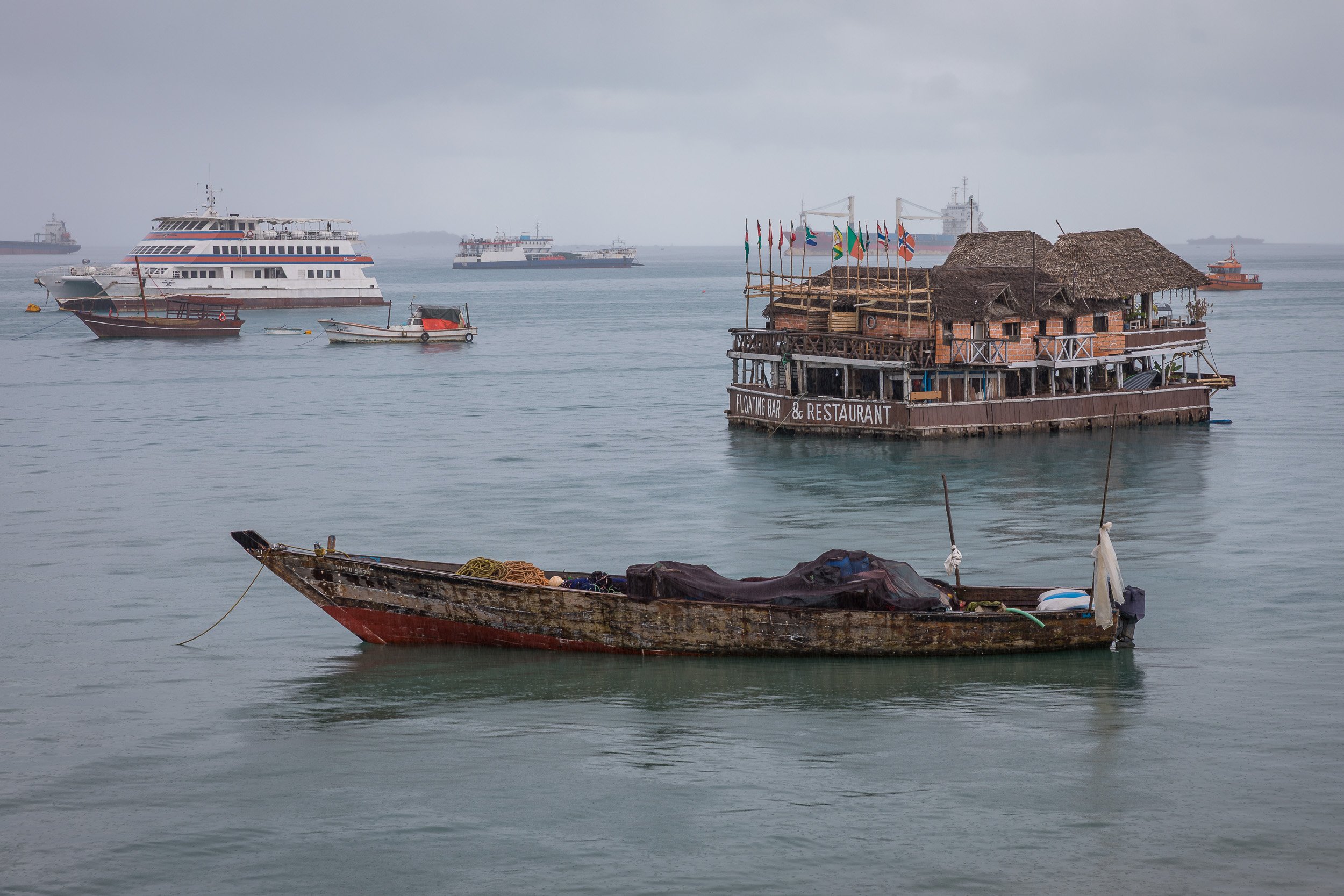 Harbour in Stone Town, Zanzibar – traditional wooden dhows and ferries lying in the turquoise Indian Ocean with the city waterfront as a backdrop.