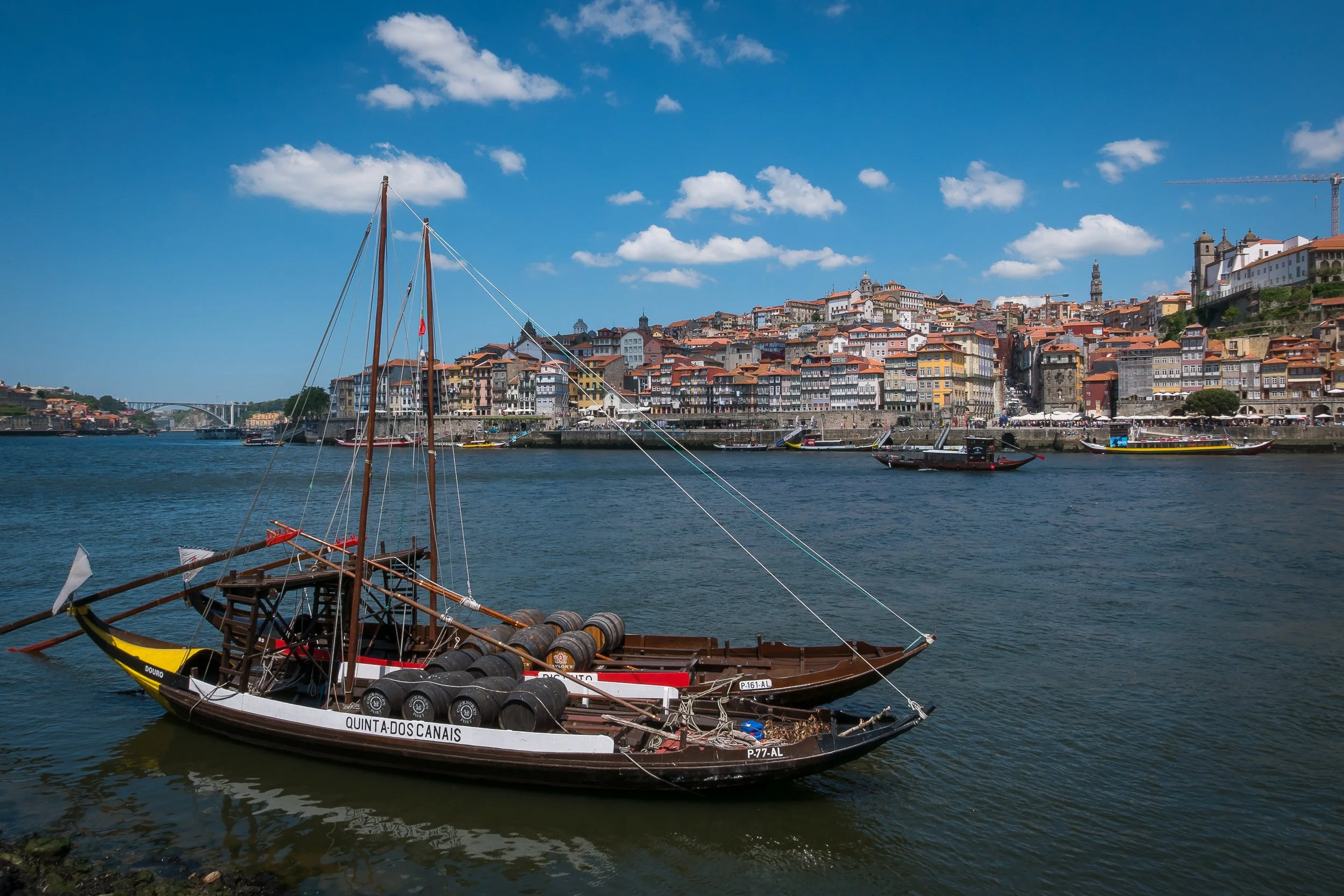 A traditional rabelo boat on the Douro River, with Porto’s Ribeira waterfront rising in layers behind it.