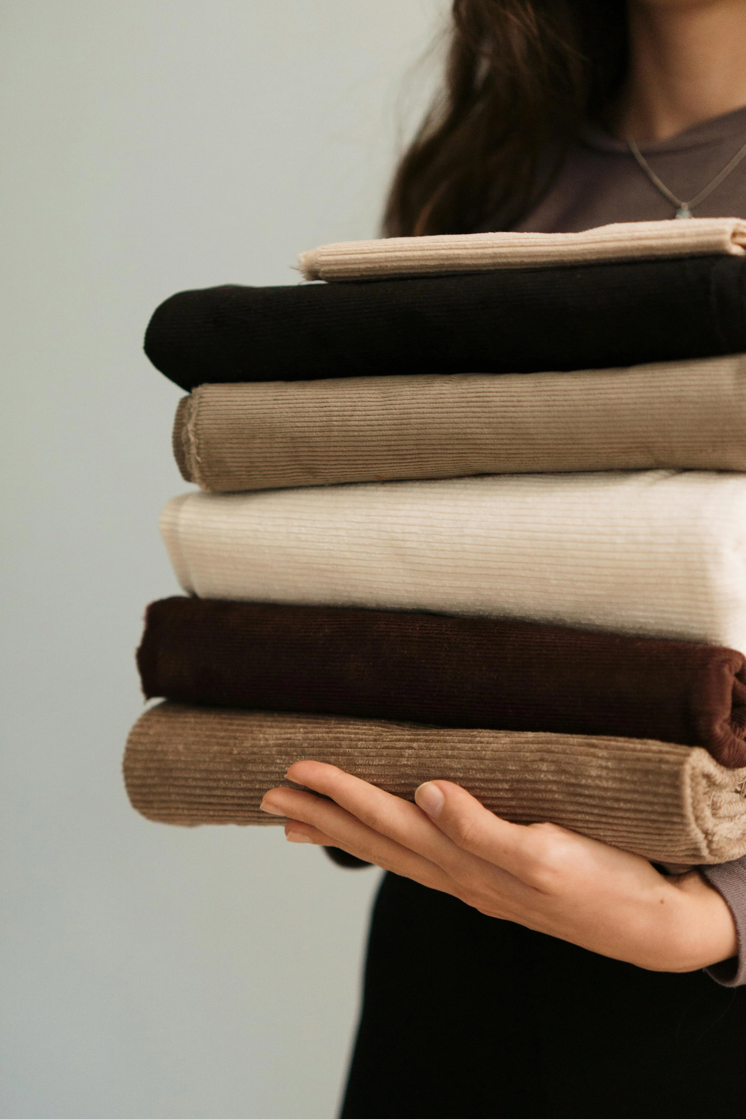 Gefaltete Kleidung in neutralen Farben als Symbol für eine kuratierte Garderobe und bewusste Stilberatung.