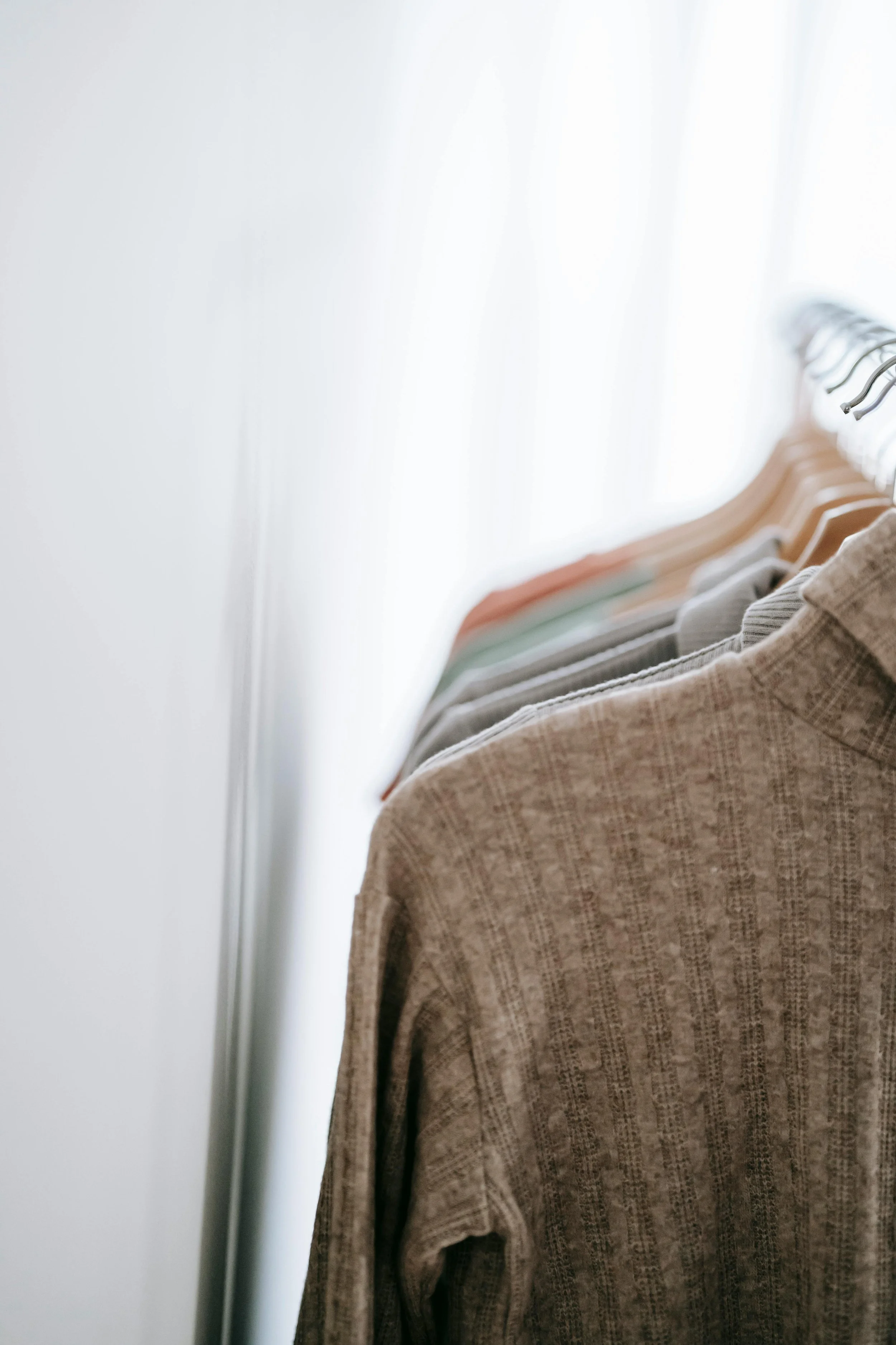 Ordentlich aufgehängte Kleidung im Kleiderschrank als Symbol für Klarheit und Struktur im persönlichen Stil.
