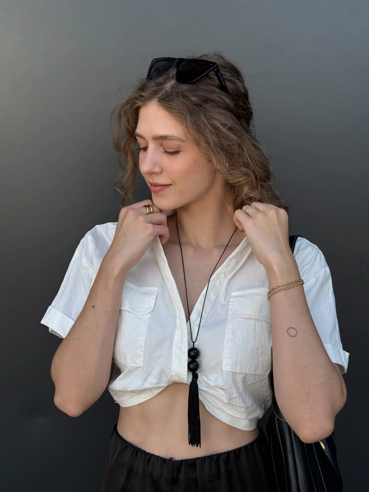 Foto von Luise Albrecht, Gründerin von The Neutral Blazer, in einer weißen Bluse mit einer schwarzen Fransenkette und Sonnenbrille