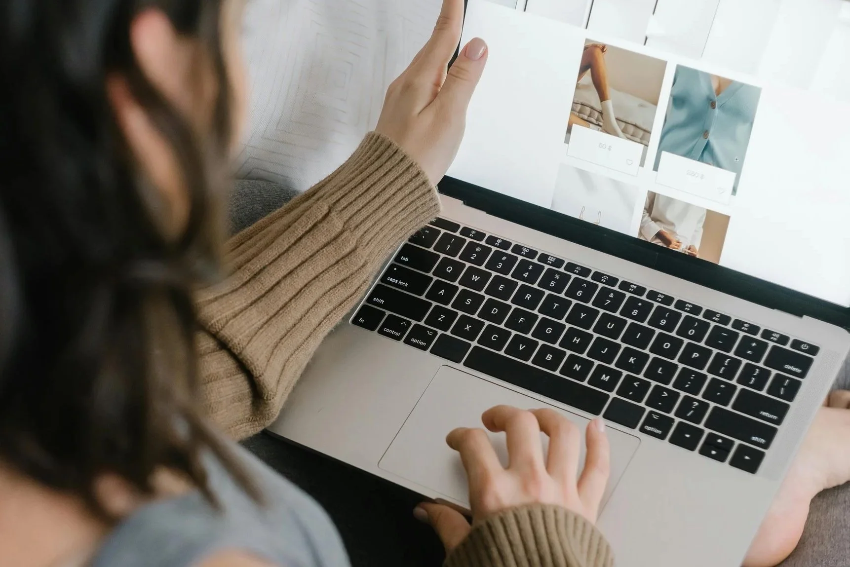 Frau wählt Kleidung am Laptop aus als Symbol für einen Gutschein für Stilberatung oder Personal Shopping.