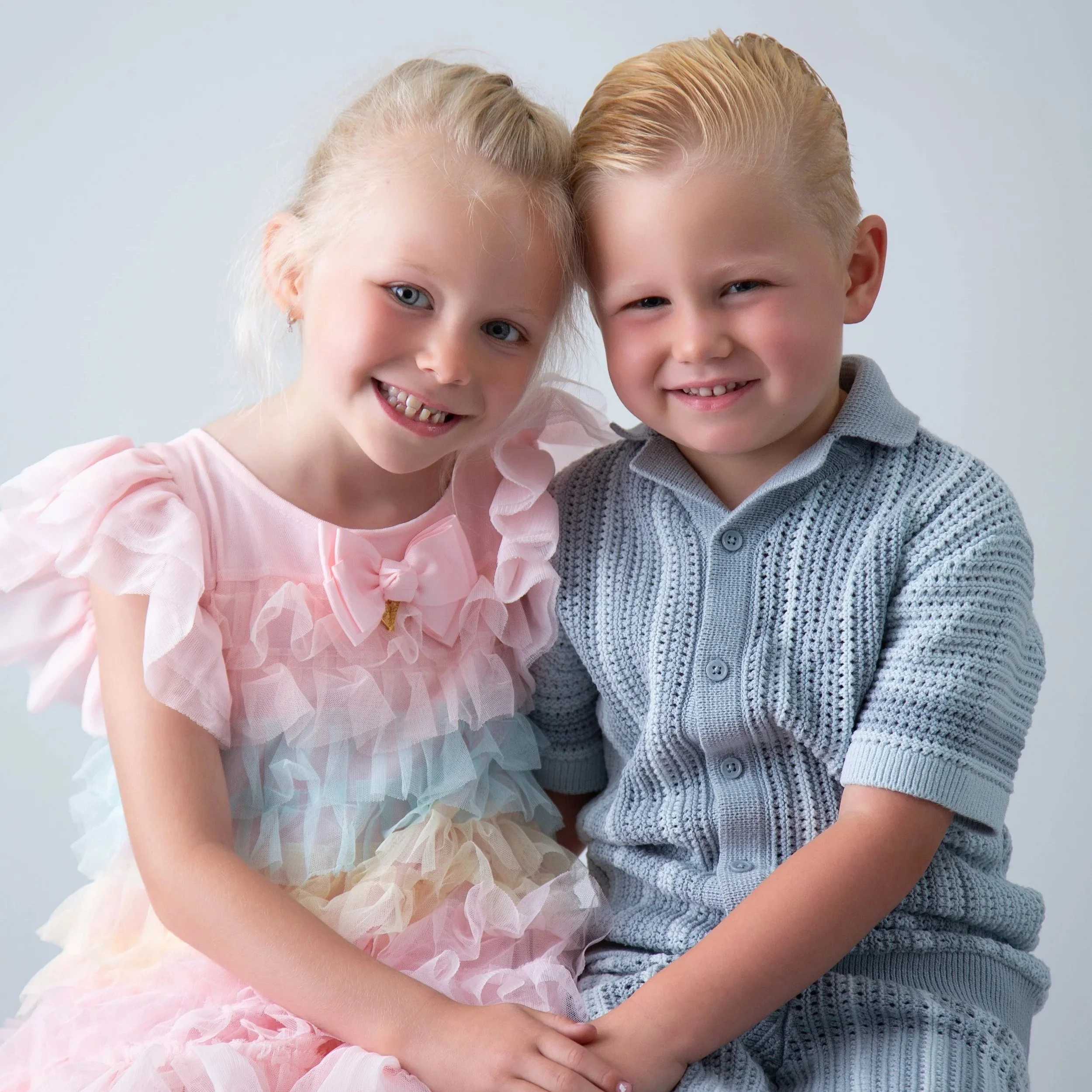 Smiling sister in a pastel tulle dress and brother in blue, sibling photoshoot in Upminster
