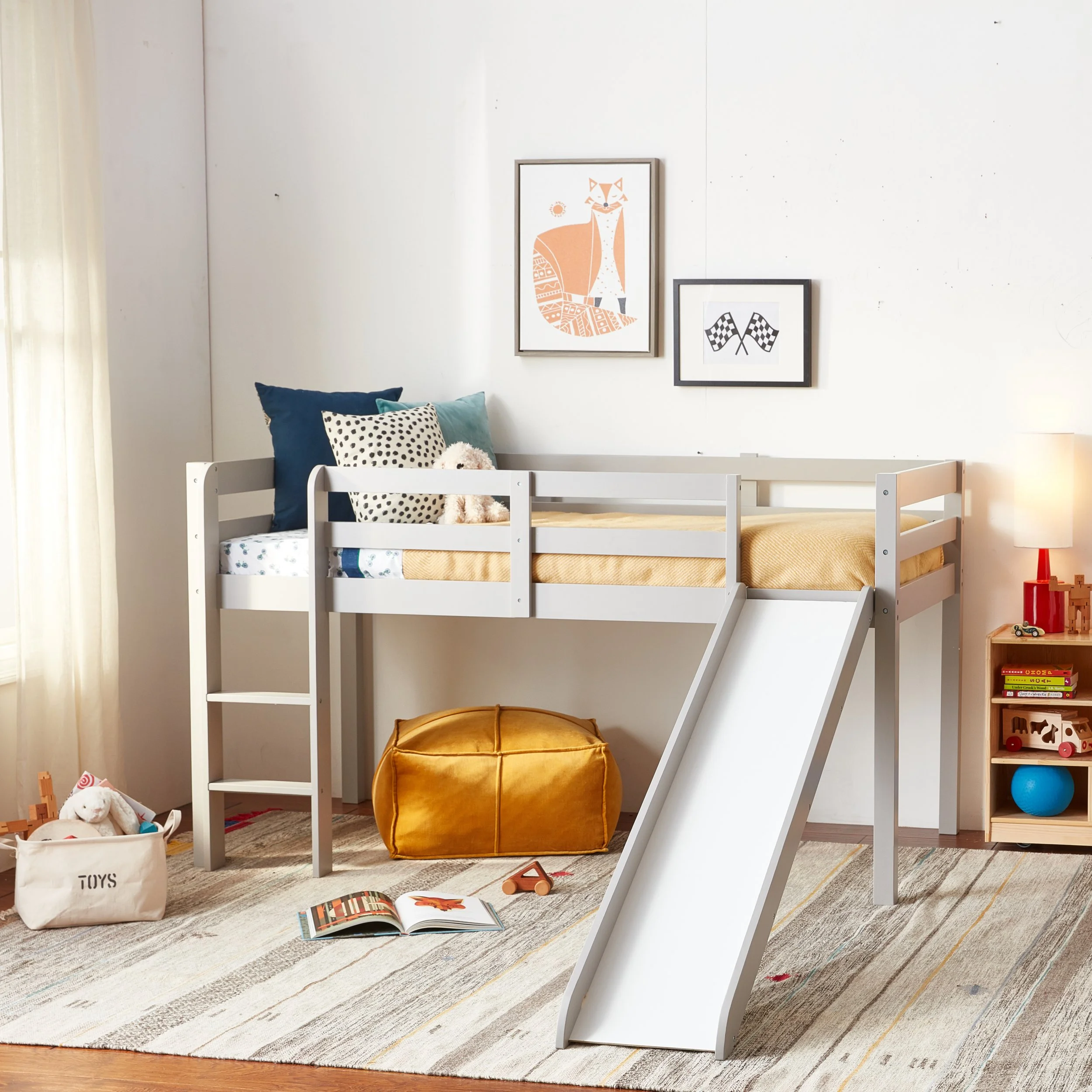 Children's bedroom with loft bed, slide, toys on the floor, and wall art.