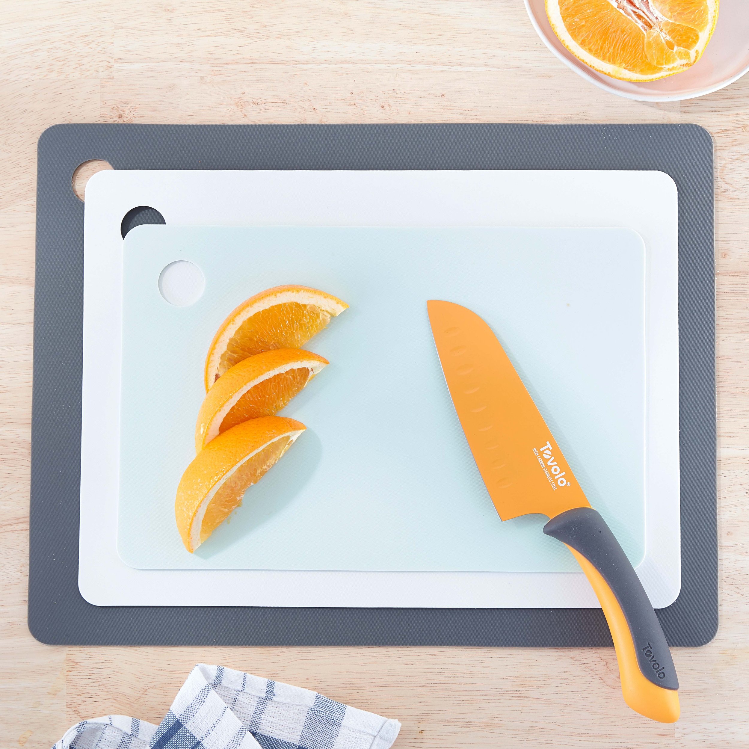 Sliced orange wedges on a cutting board with a orange-handled knife beside them.