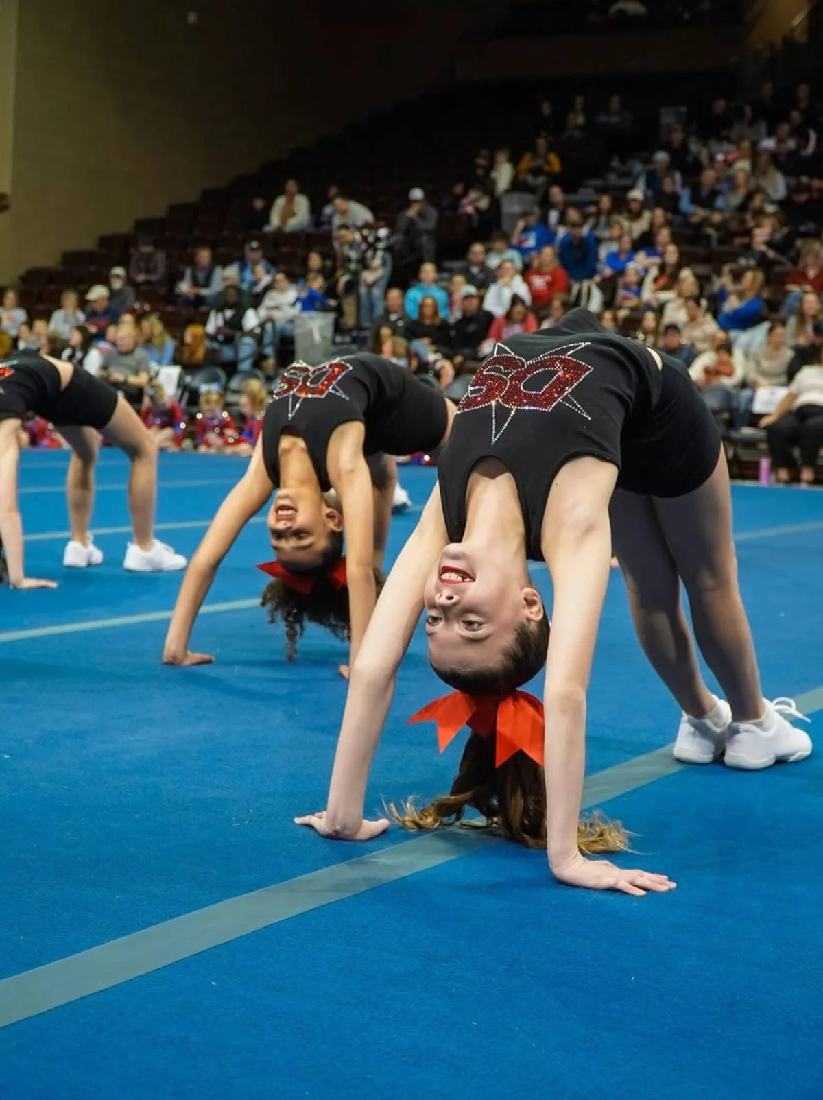 Cheer students performing a tumbling maneuver.