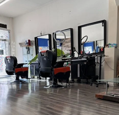 Wide-angle view of A&B Barbershop’s interior in Chicago, featuring
multiple barber chairs, mirrors, and natural light from the front
windows.