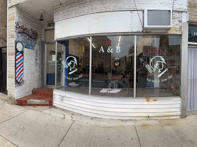 Exterior of A&B Barbershop in Chicago with large front windows,
barber graphics, and an open sign welcoming walk-ins.