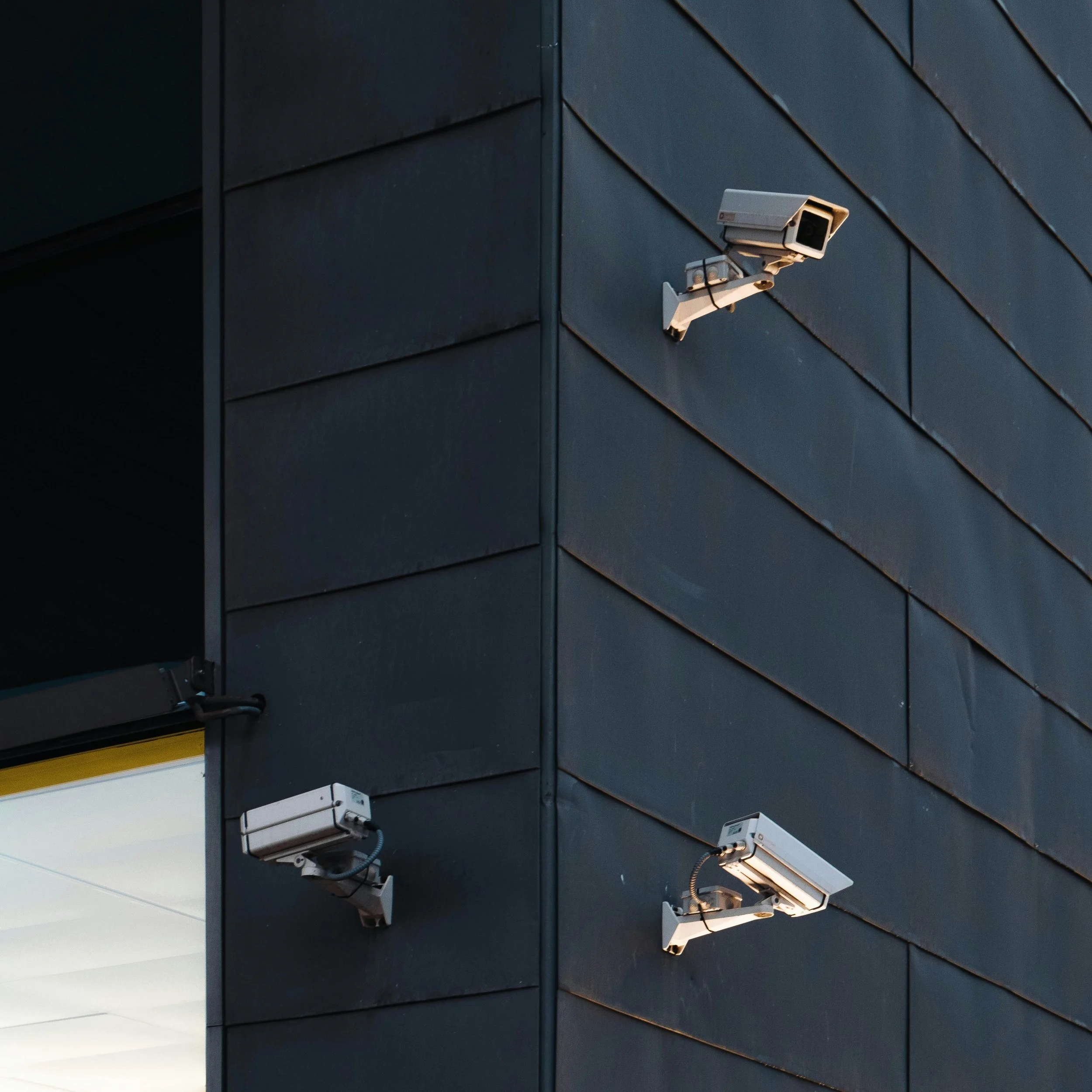 Three security cameras mounted on a dark gray building corner